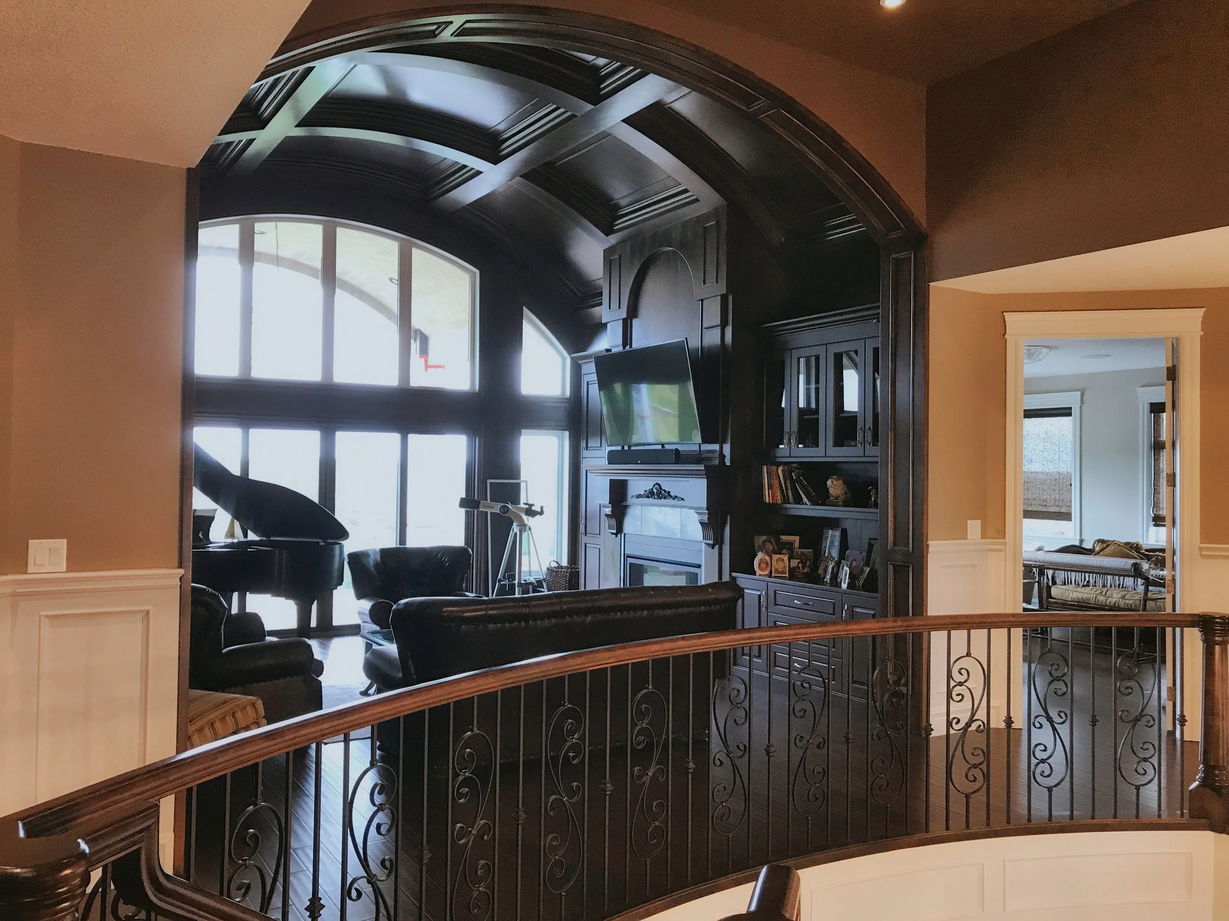 Elegant living space featuring arched window, coffered ceiling, and built-in entertainment center.