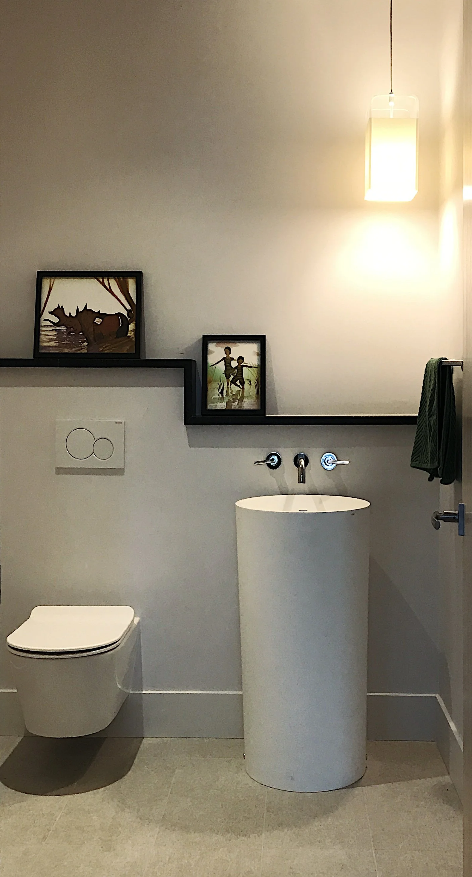 A modern powder room with floating toilet and pedestal sink