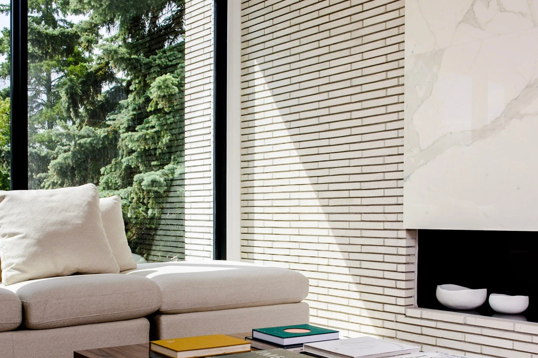Modern living room with neutral sectional sofa, floor-to-ceiling windows, and minimalist fireplace.