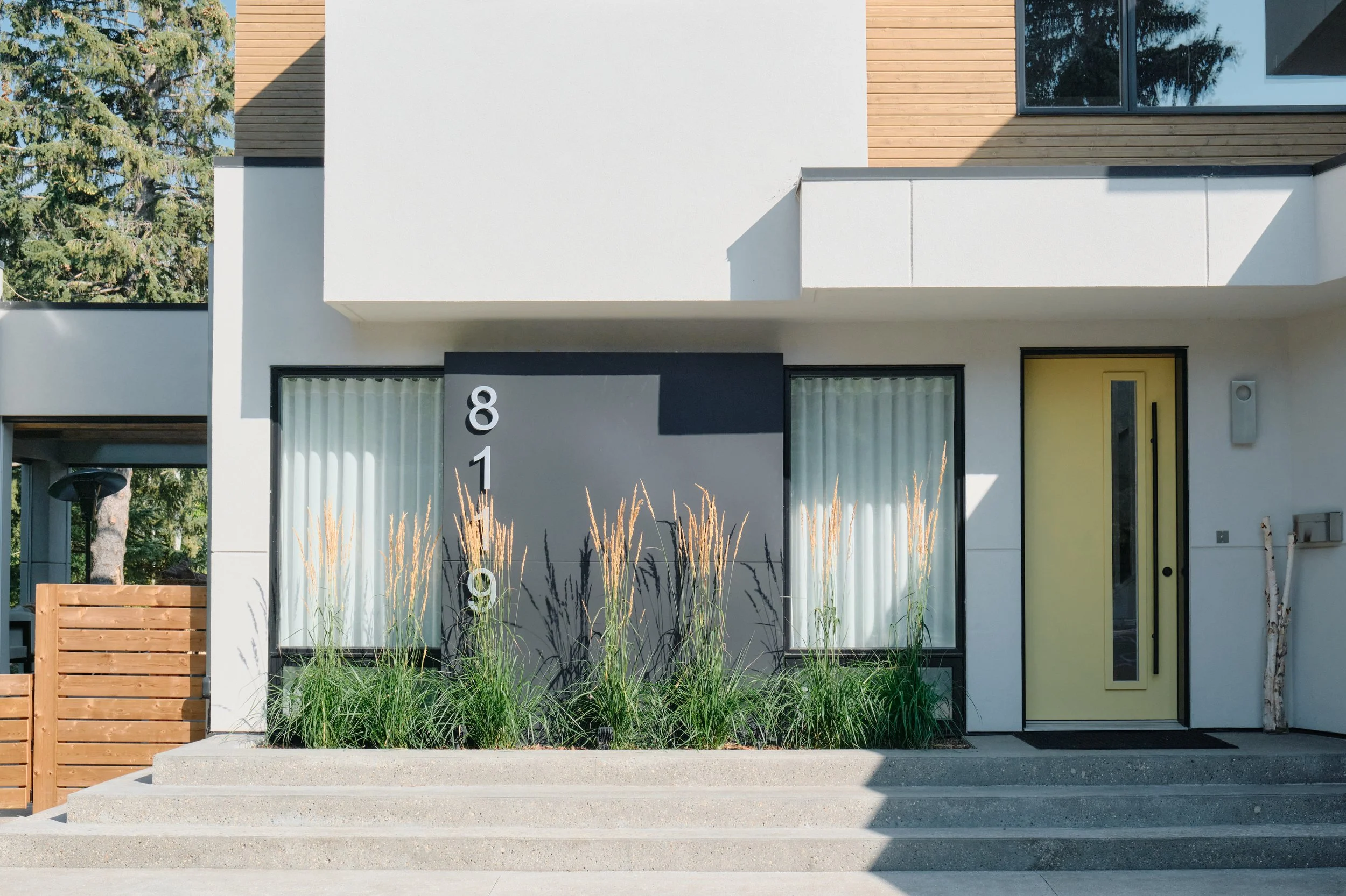 A modern home with white stucco and a yellow door