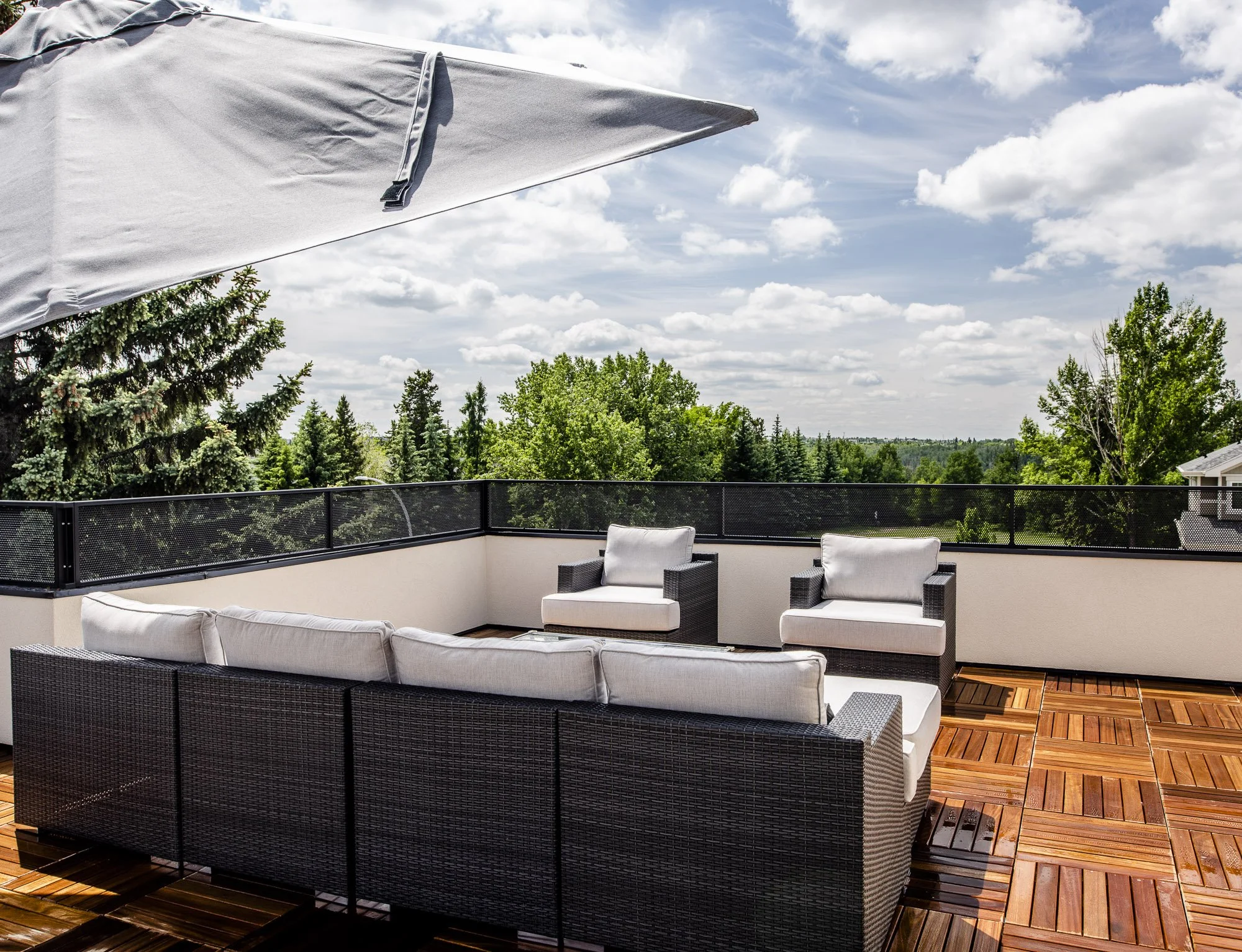 High-end rooftop patio design with outdoor sectional seating, lounge chairs, and natural wood deck.