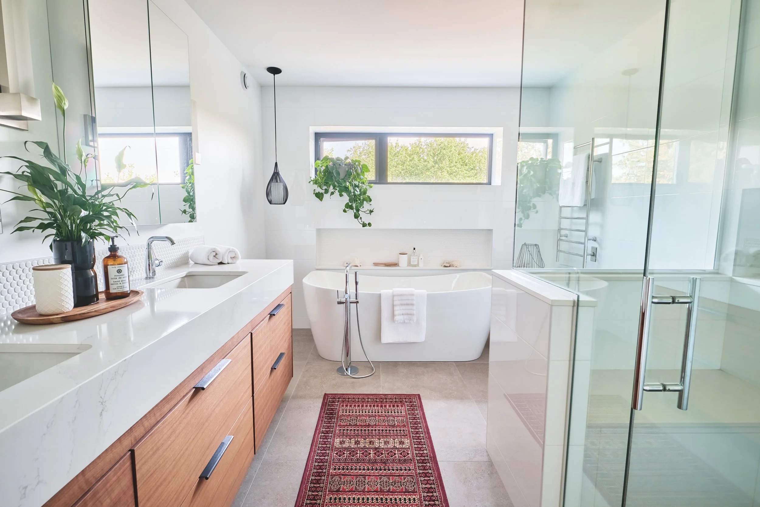 Stylish bathroom showcasing floating vanity, black pendant light, and open-concept shower design.