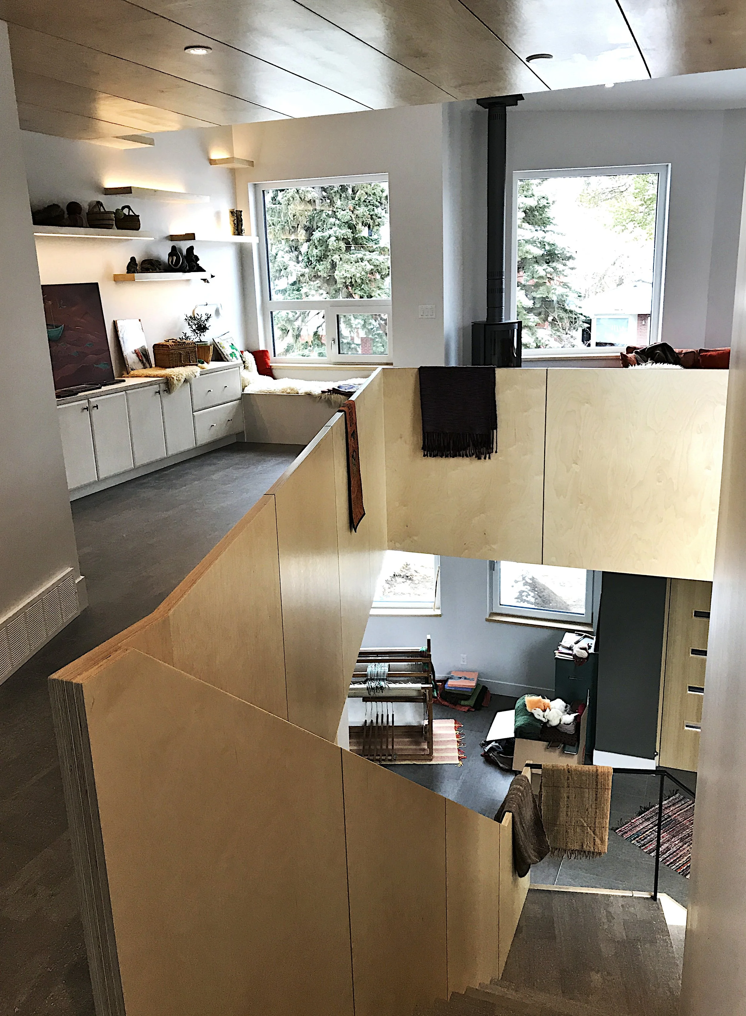 Modern multi-level home interior with wood staircase, cozy reading nook, large windows, and crafting area—features natural light, minimalist design, and warm wood finishes ideal for creative living spaces