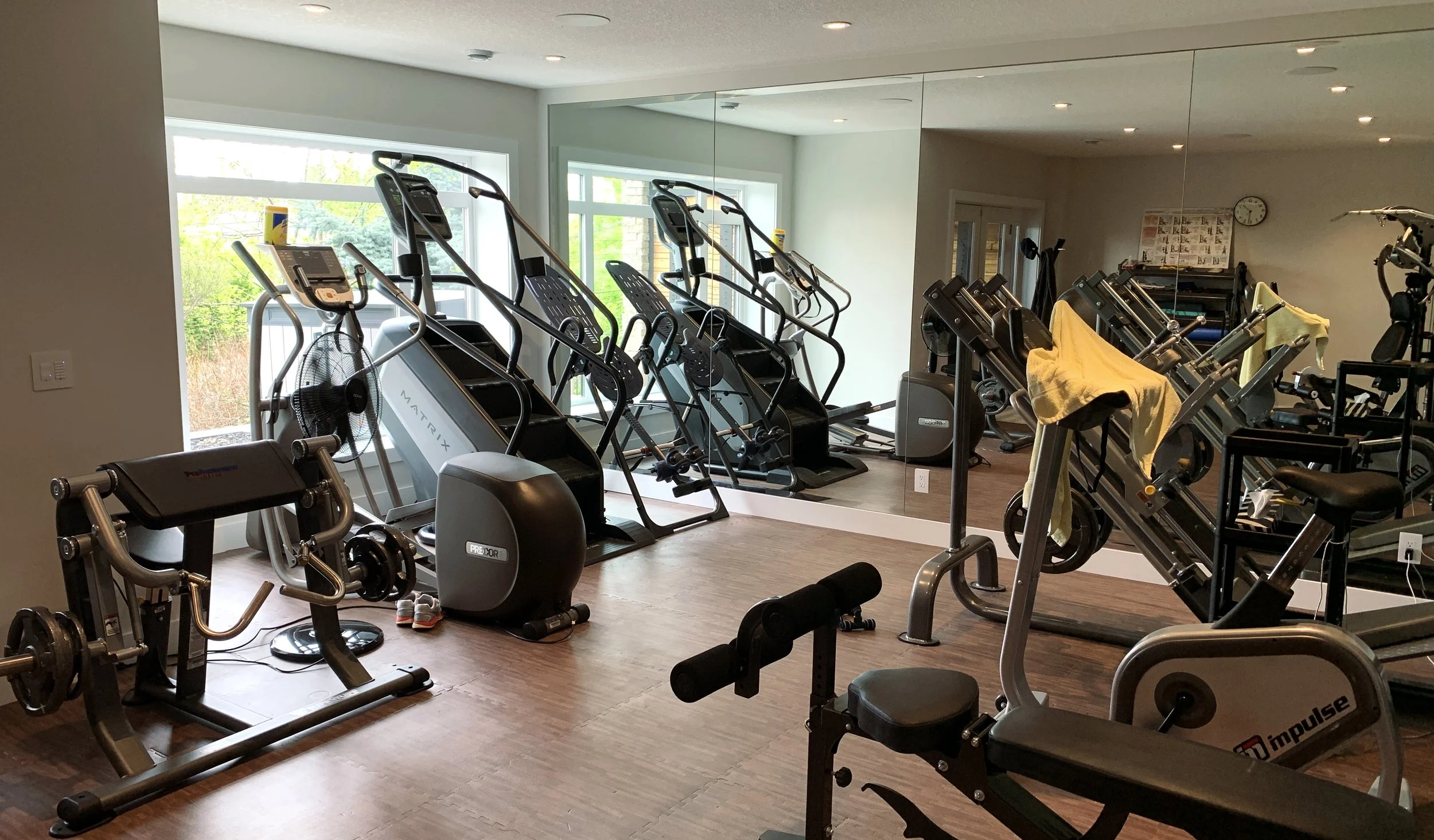 Indoor gym with stair climbers, leg curl machine, stationary bike, and mirrored wall