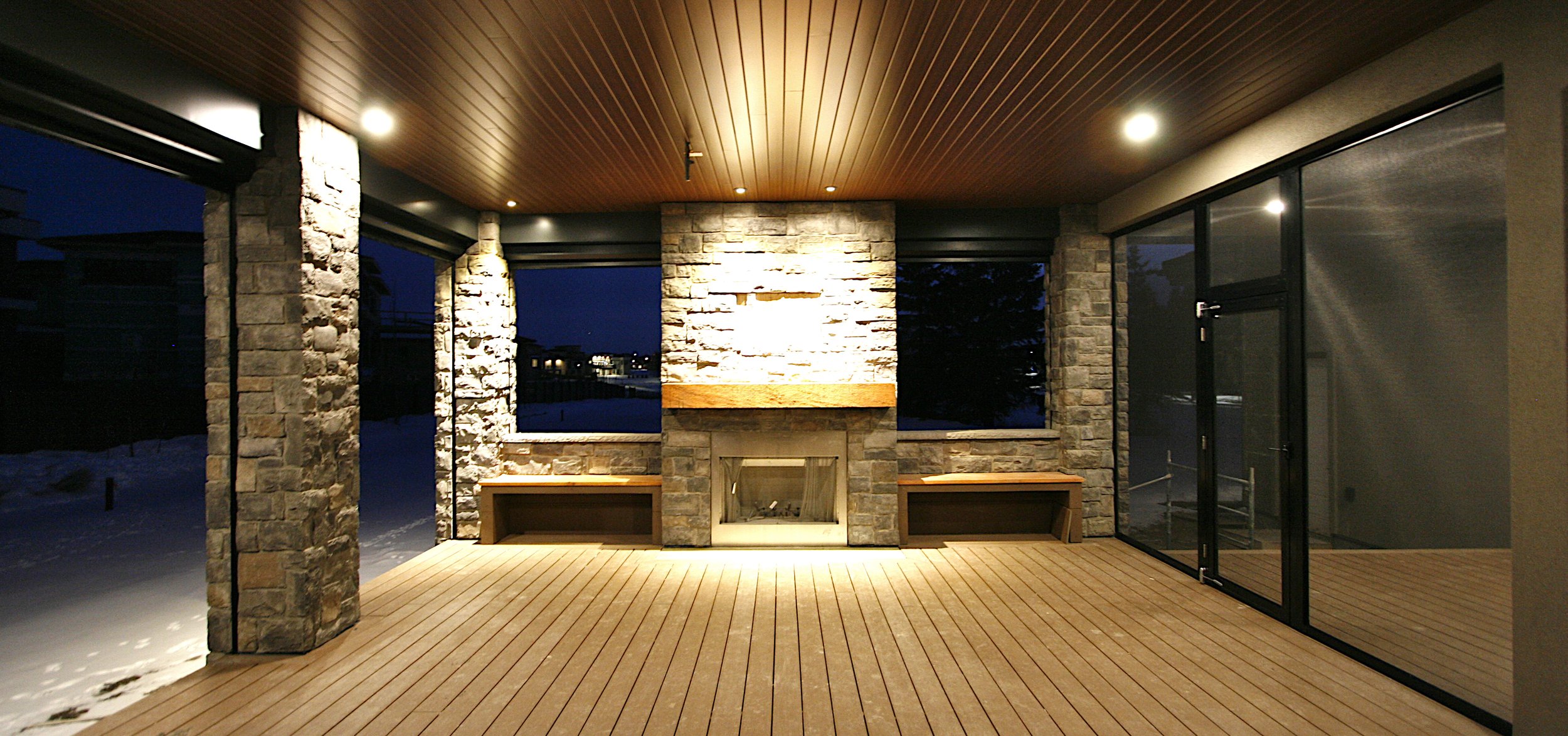 A covered exterior deck with fireplace and powered screens.
