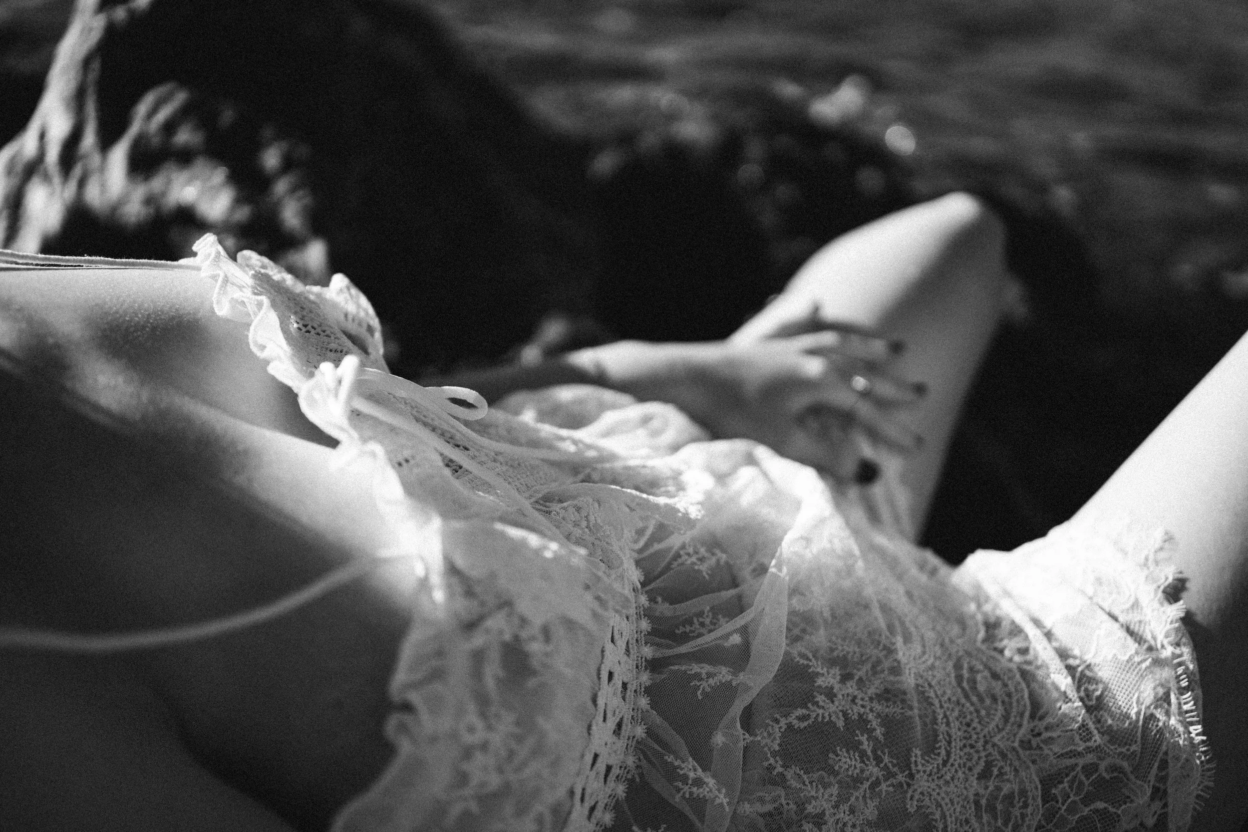 Close-up of lace fabric and ribbon on a garment, possibly a wedding dress, in black and white.