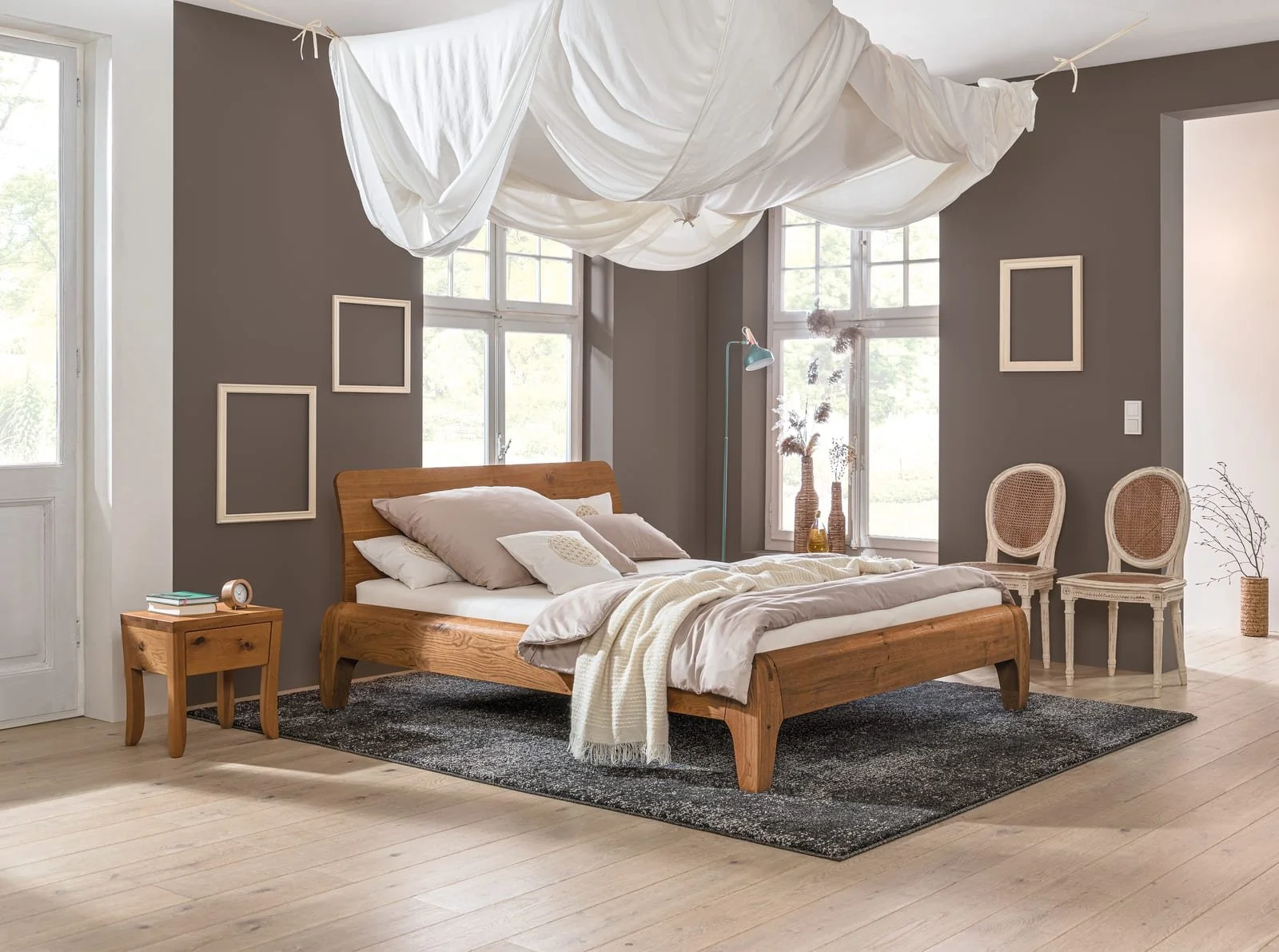 Dormiente Gonda solid oak bed under a linen canopy