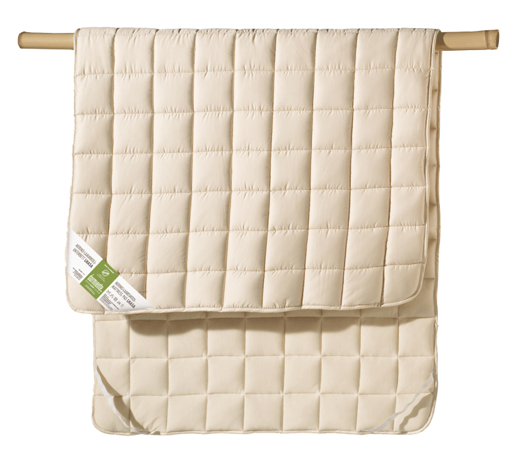 Beige quilted mattress cover hanging over a wooden rod.