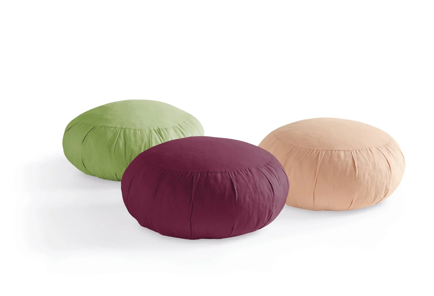 Three round meditation cushions in green, plum and apricot