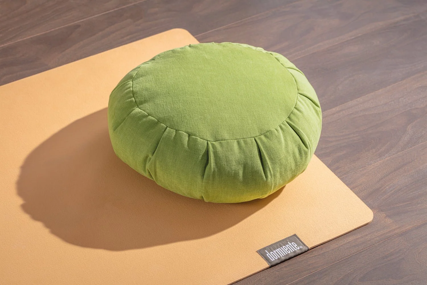 Green meditation cushion on an apricot yoga mat