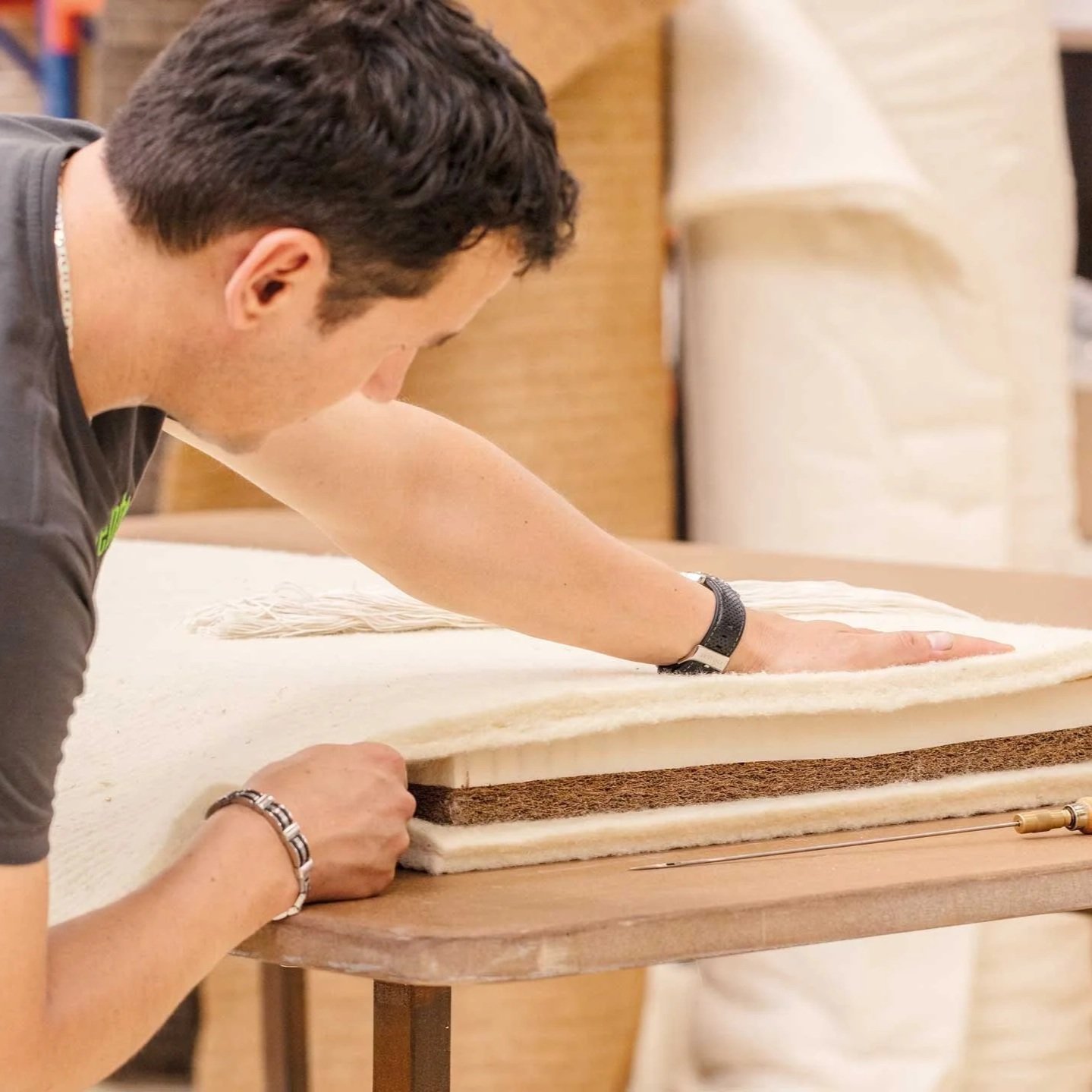 A person working with a layered piece of fabric or felt on a table, using their hands to smooth or shape it.