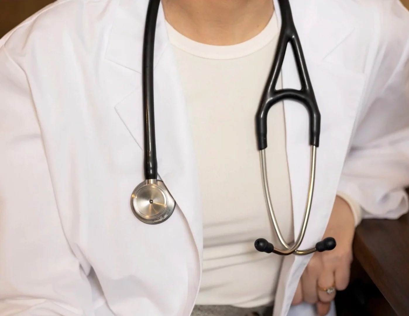 Close-up of a healthcare professional wearing a white coat and a stethoscope around their neck.