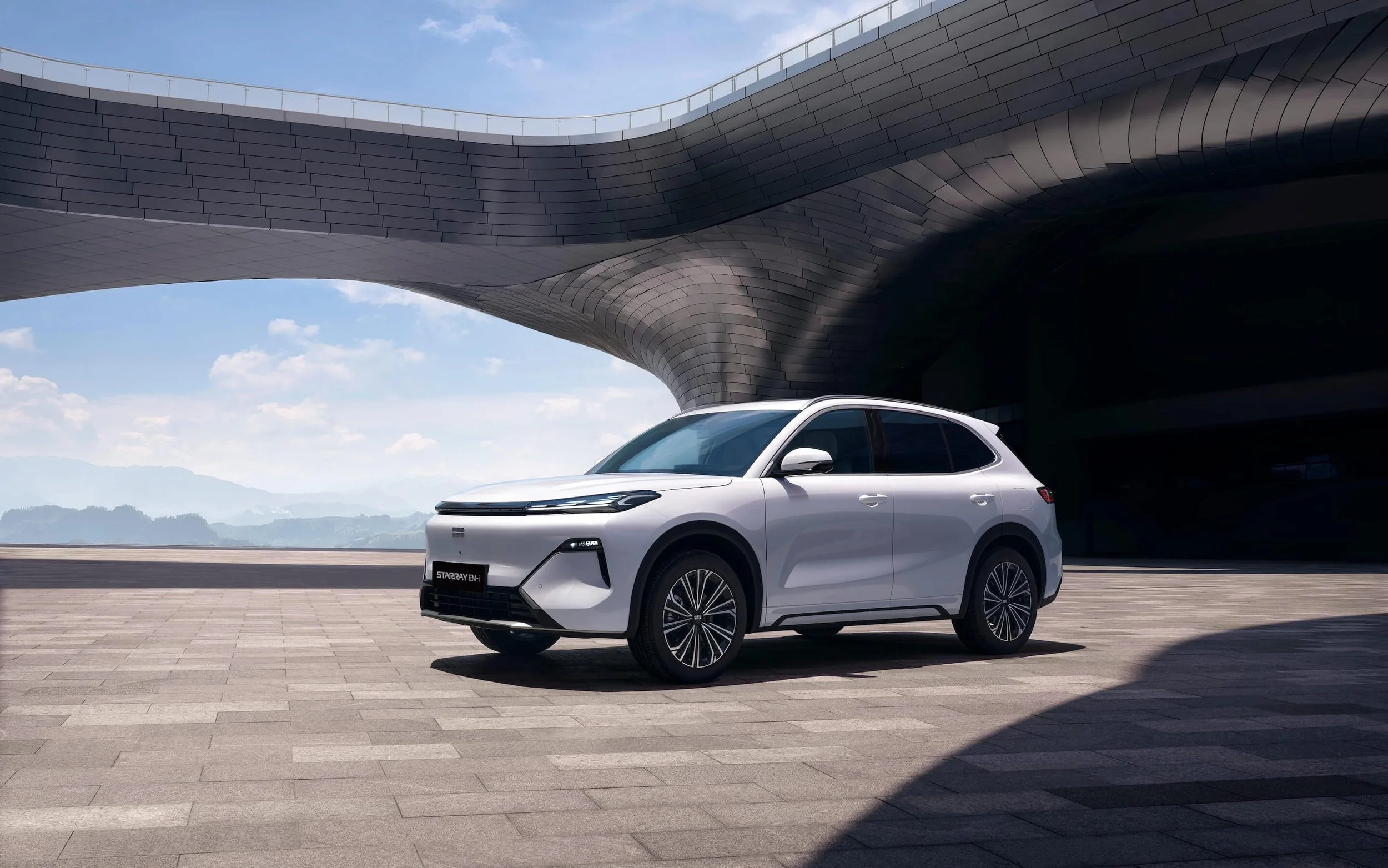 Coche eléctrico blanco en plaza amplia frente a estructura moderna de arquitectura futurista.