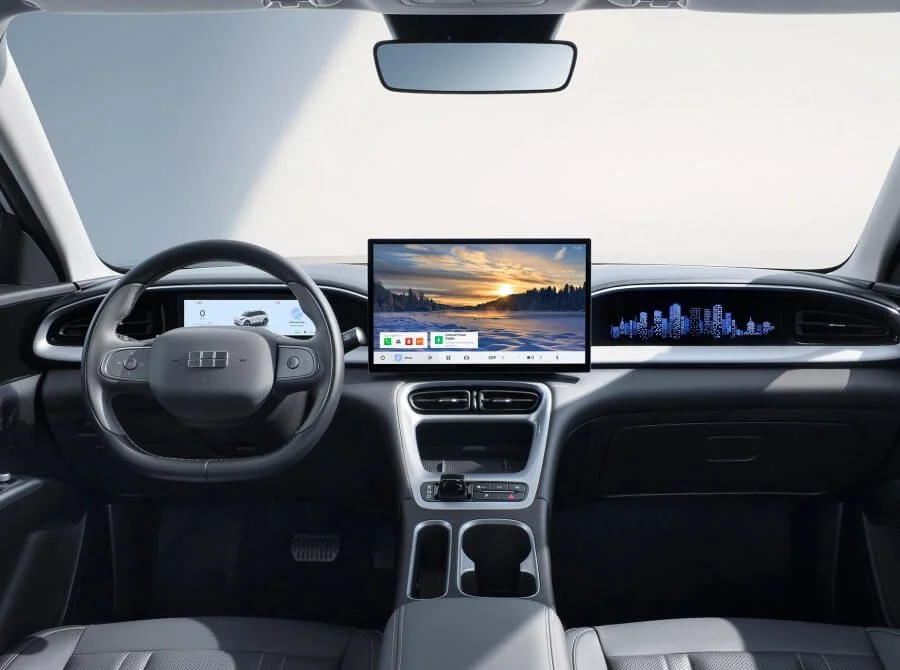 Interior de un automóvil moderno con volante, pantalla digital central mostrando la vista al atardecer y un diseño futurista del tablero.