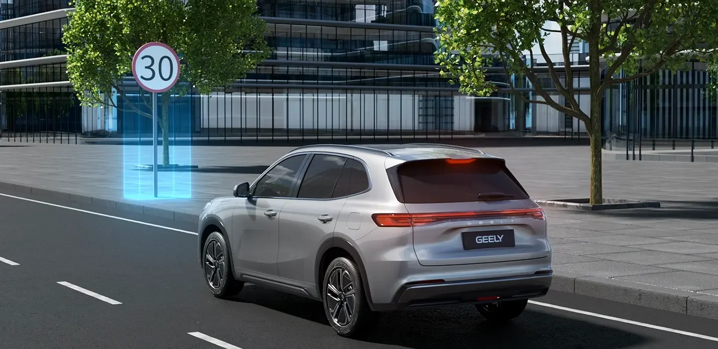 Coche plateado avanzando por una calle urbana con señal de límite de velocidad de 30 km/h y árboles en el lado de la acera