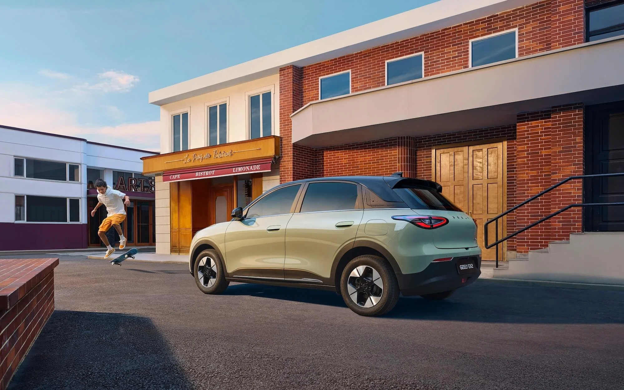 Un niño haciendo trucos con su patineta en la calle frente a un edificio de ladrillos y un restaurante, con un automóvil eléctrico estacionado delante.
