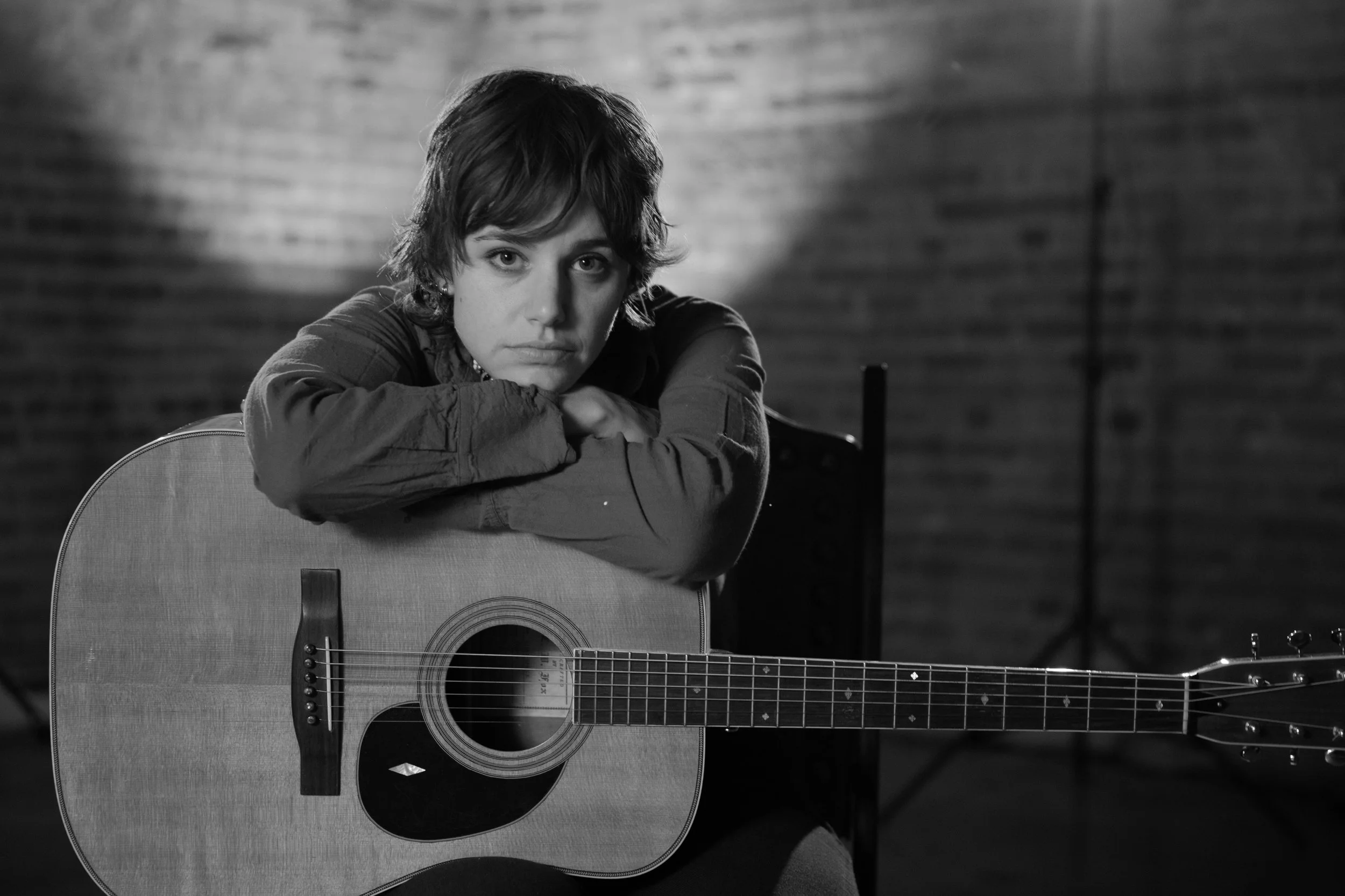 Canadian folk musician Cat Clyde in a photograph in a dark room with backlight.