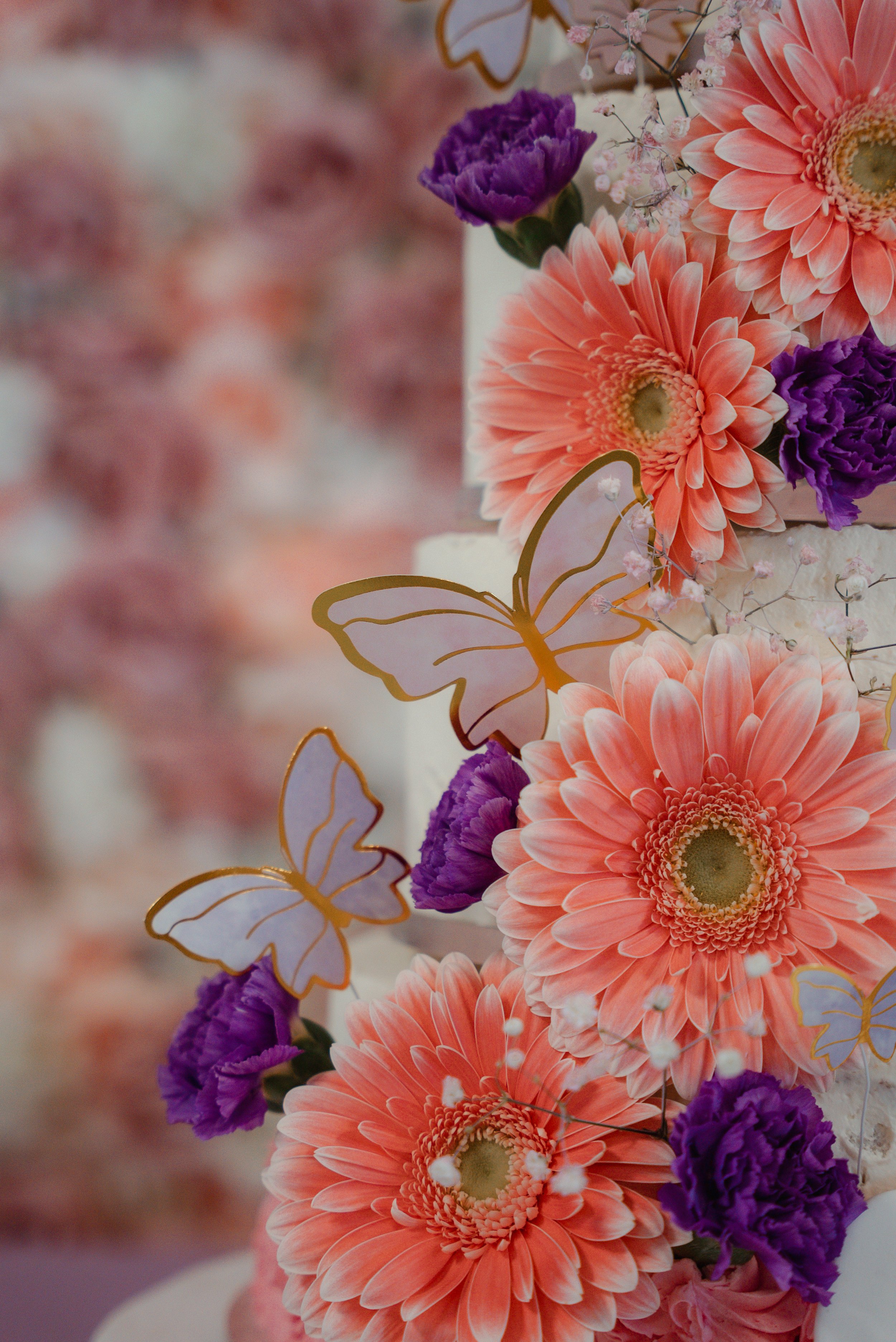 Fleurs roses, violettes et décorations en forme de papillons sur un gâteau de mariage.