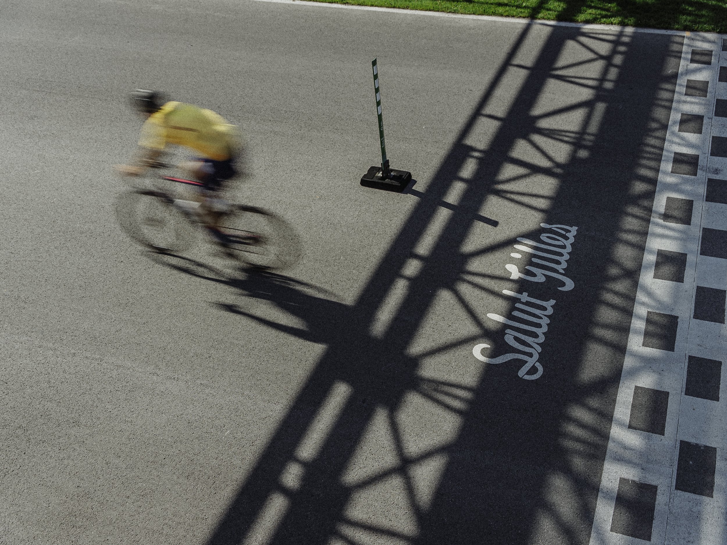 Véliplayeur passant devant une ligne de départ avec l'inscription "Sortie vélo" à Savoy Joux, sous l'ombre d'une structure métallique.