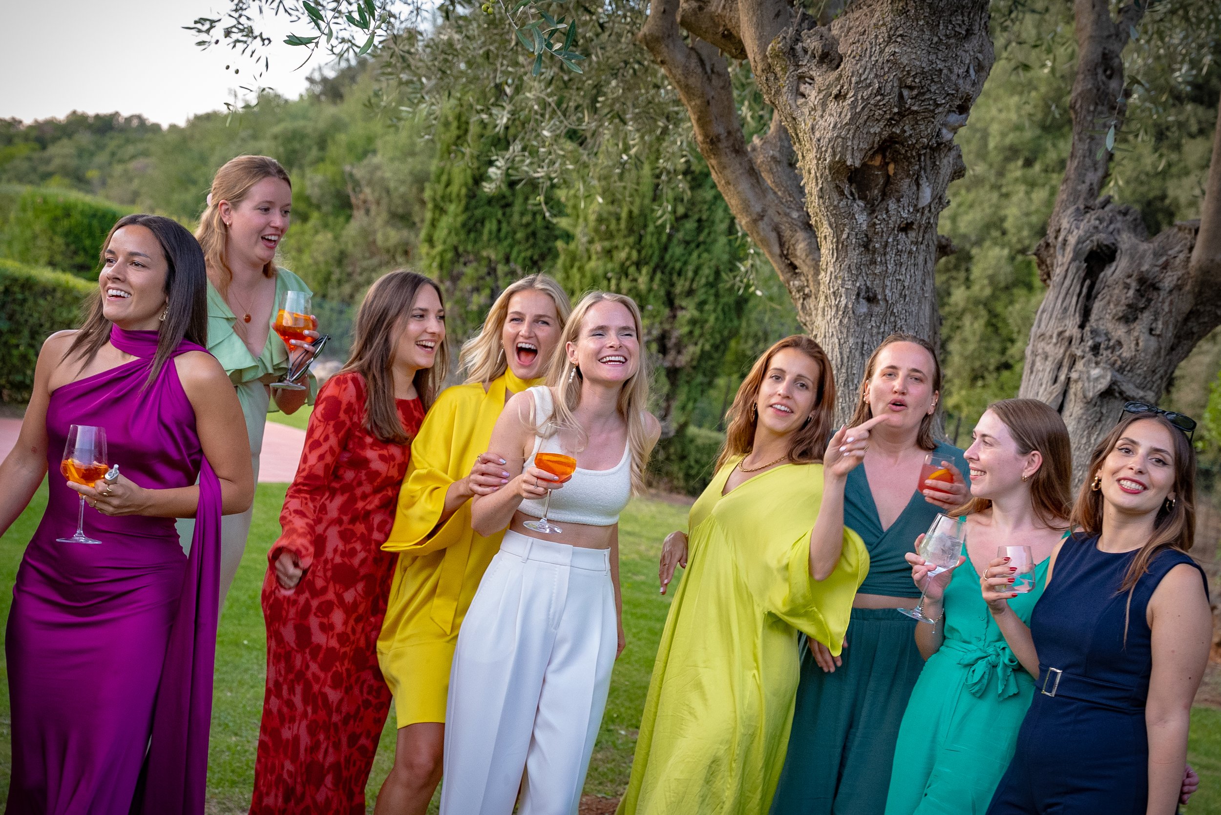 Groupe de femmes souriantes et costumées lors d'une fête en plein air sous un arbre.