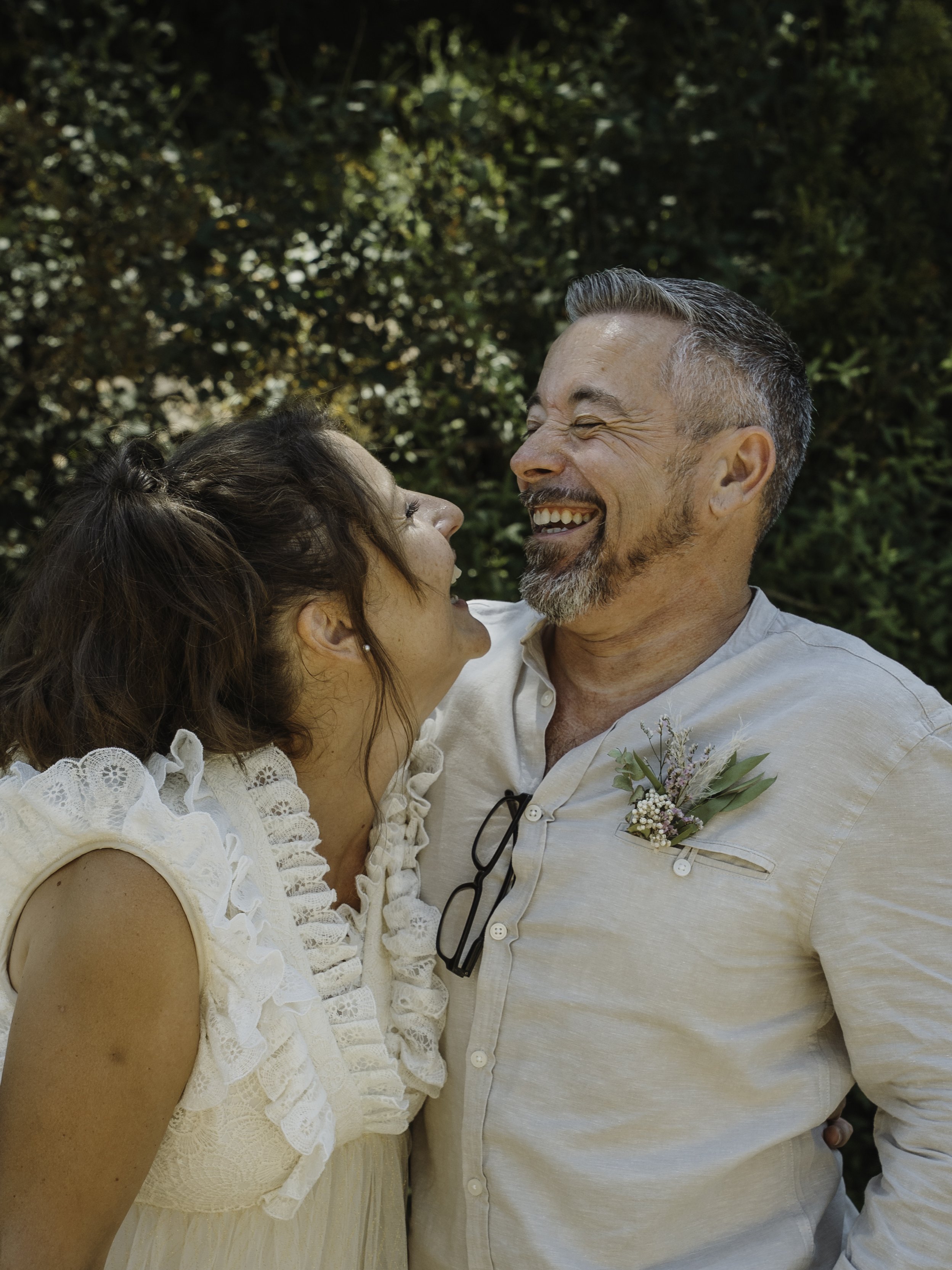 Un couple souriant, partageant un moment heureux en extérieur, avec des arbres en arrière-plan.