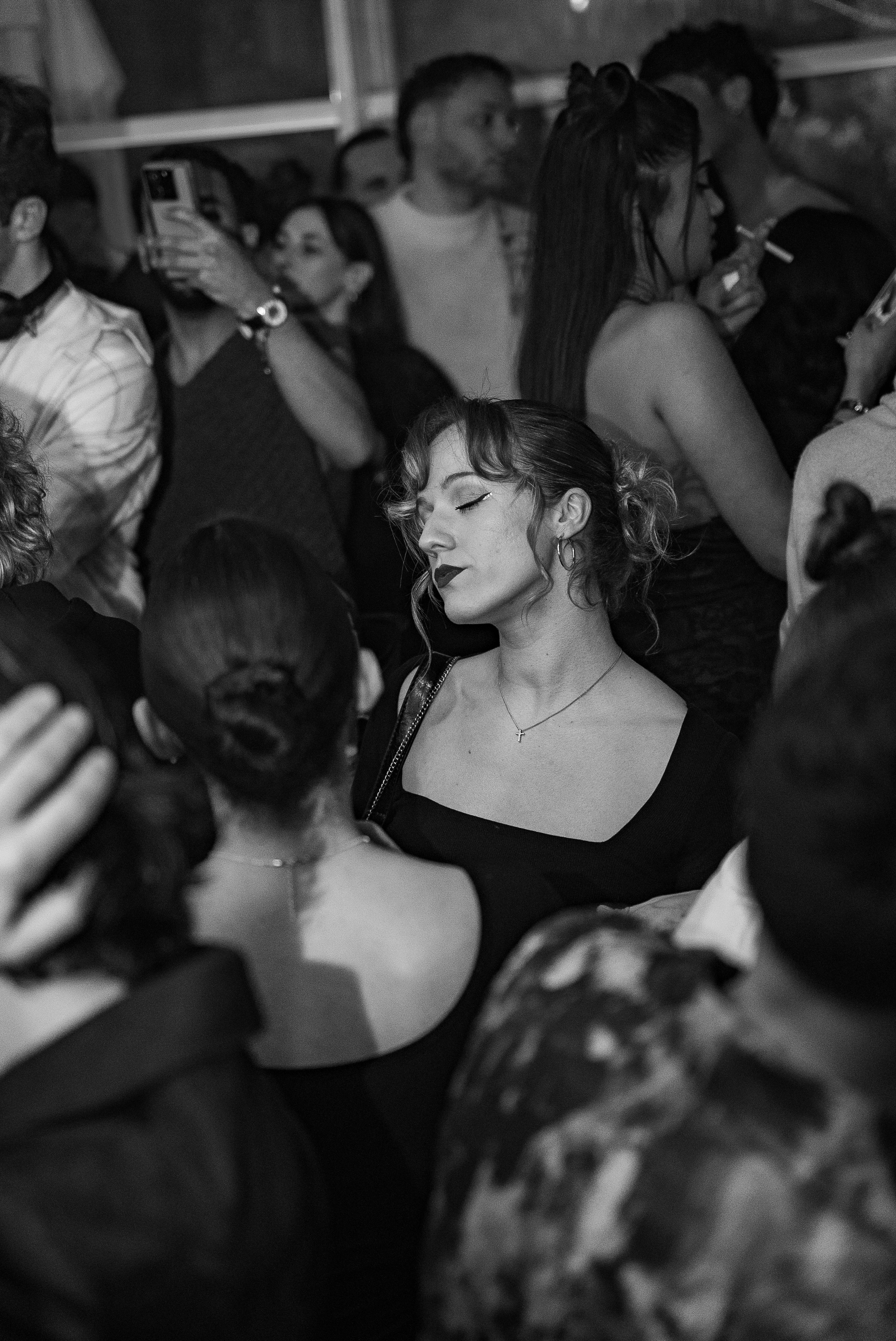 Une femme avec des cheveux bouclés et une expression sereine dans une foule de personnes.
