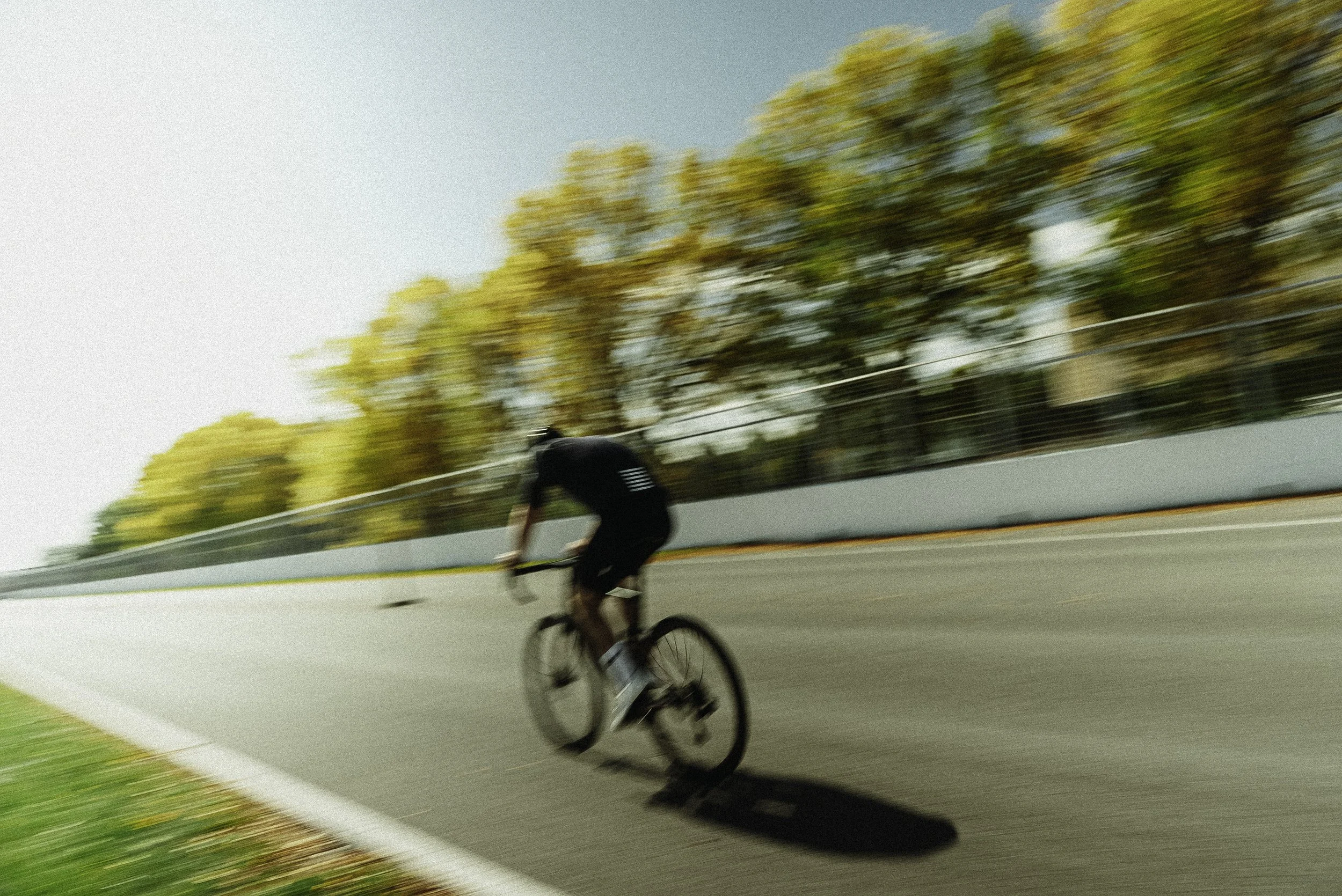 cycliste en course sur une piste en plein air avec des arbres aux couleurs automnales en arrière-plan
