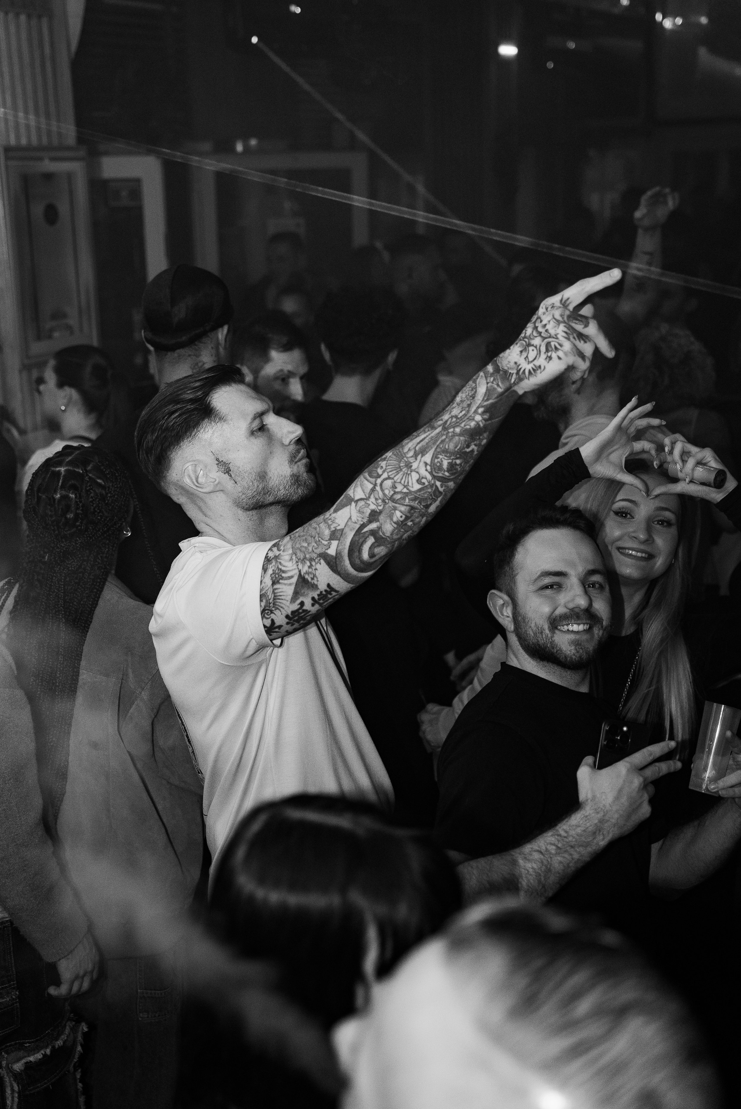 Groupe de personnes dansant et souriant lors d'une fête ou concert, photo en noir et blanc.