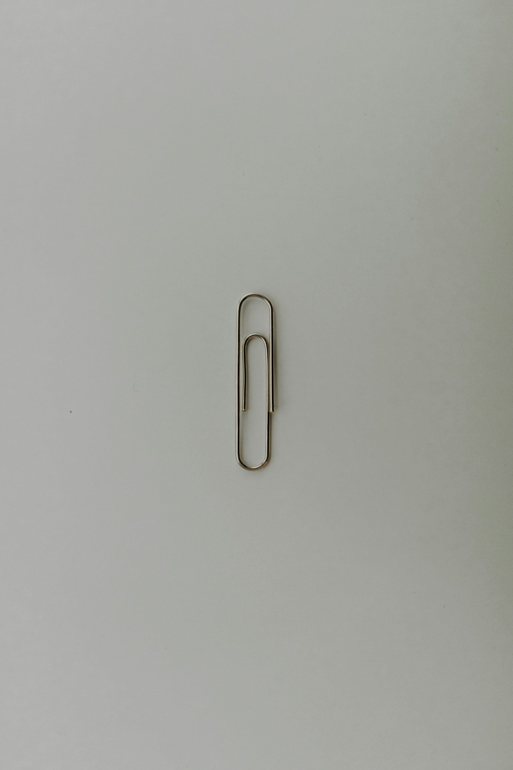 Two paperclips, one inside the other, placed on a plain white surface.