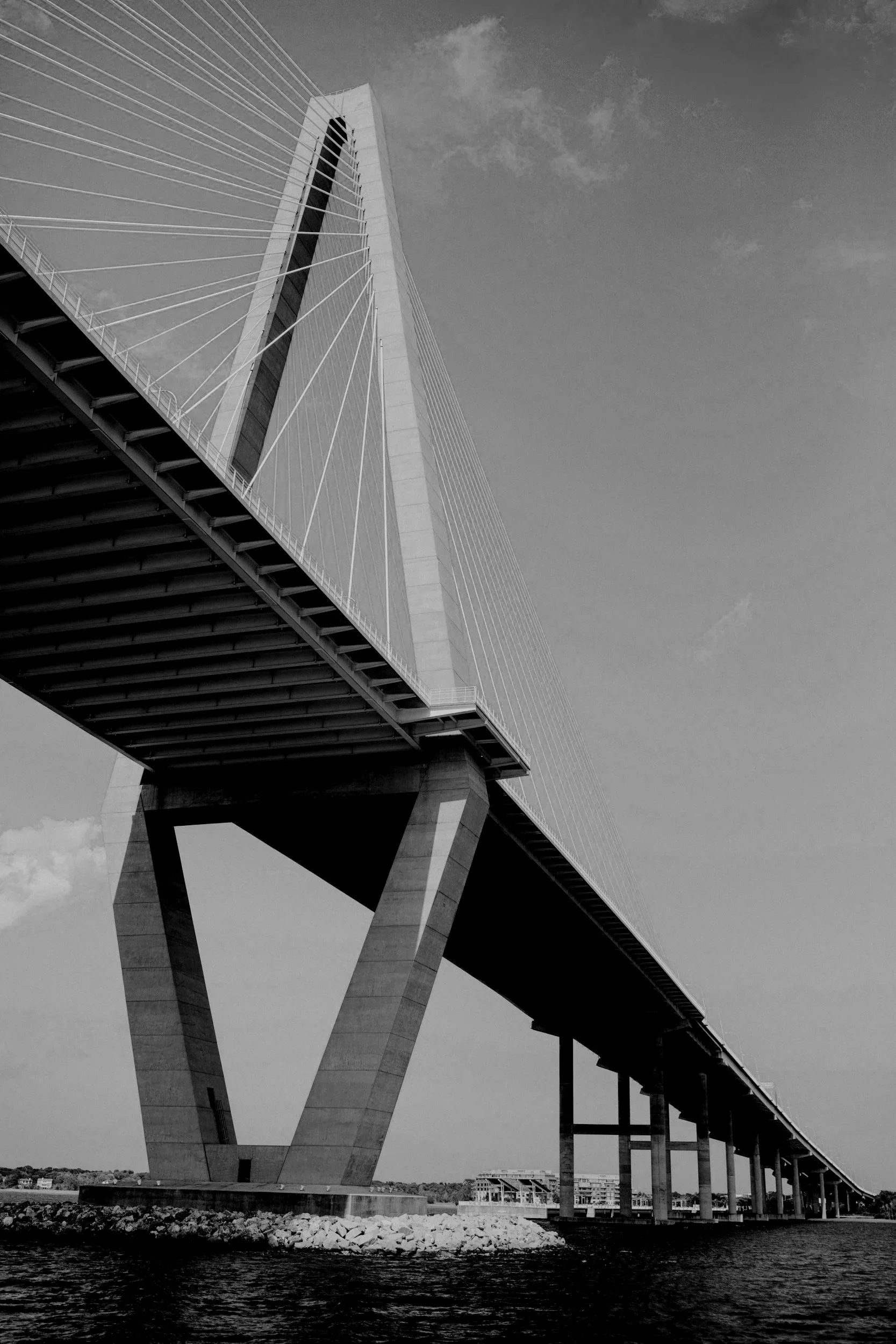 A black and white photo of a modern cable-stayed bridge over water, with tall pylons and supporting cables.