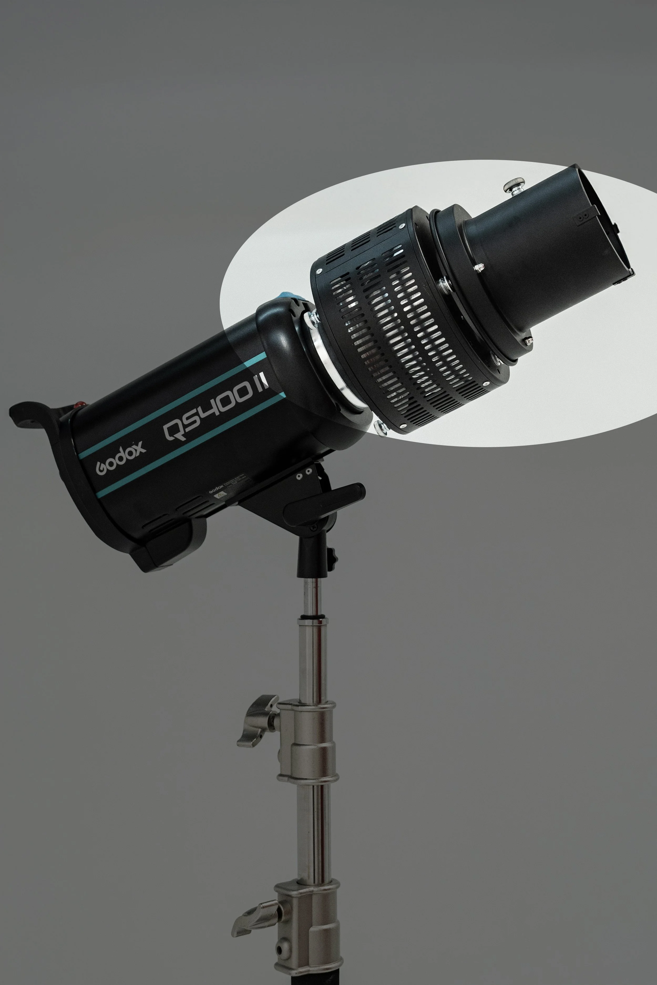 Studio lighting equipment on a stand with a gray background and a white oval reflector.