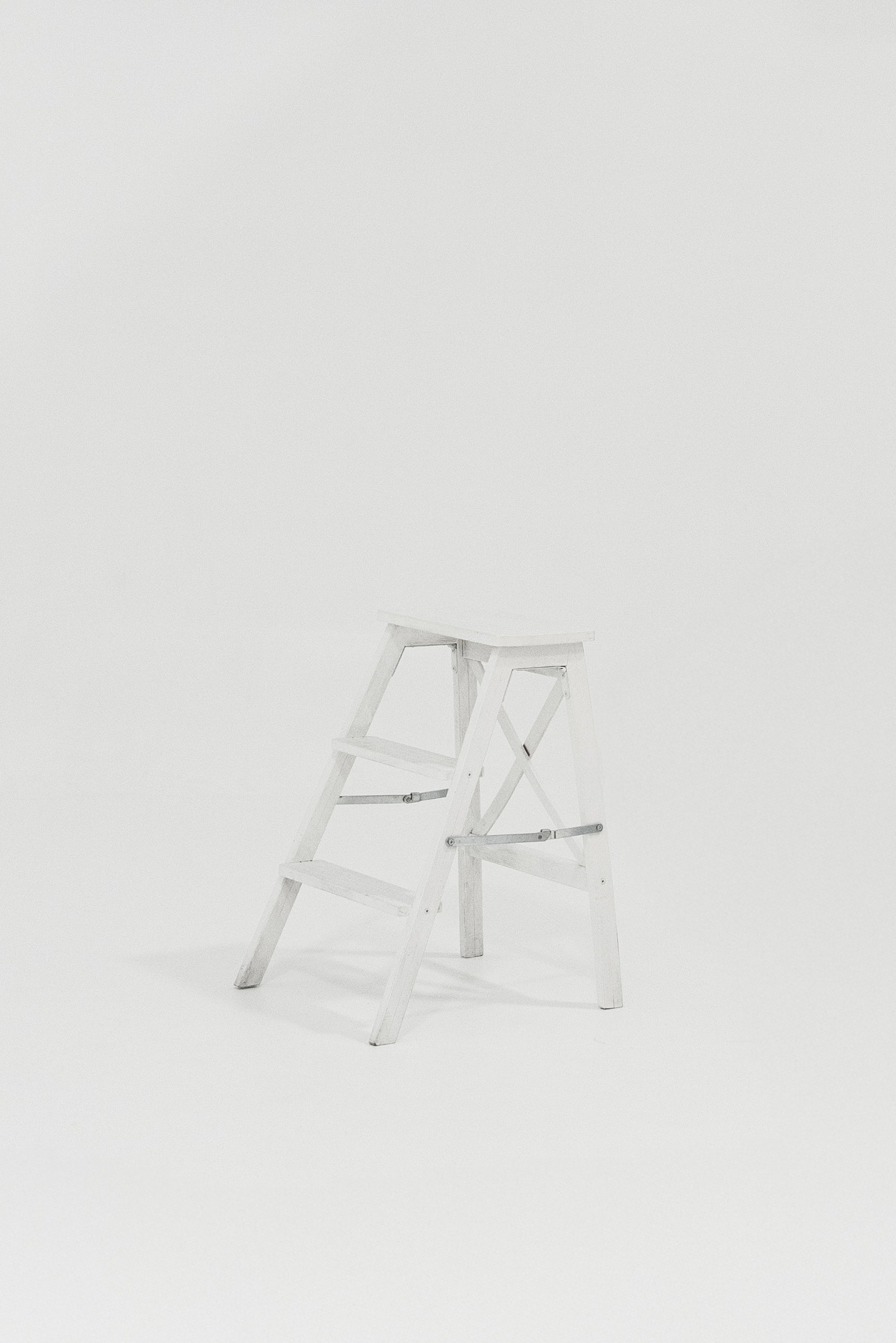 A small white step ladder with three steps, set against a plain white background.