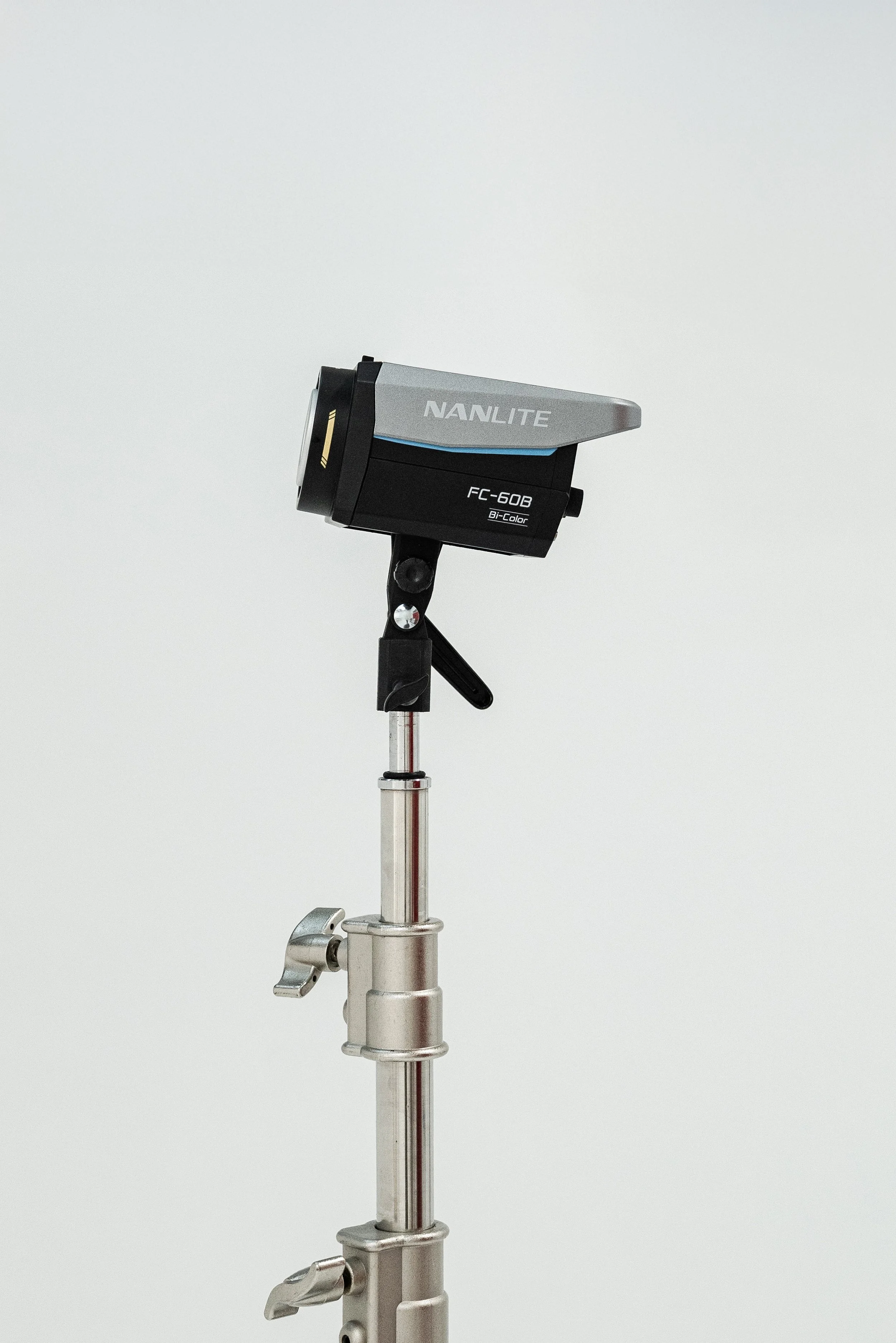 A studio light mounted on a metal stand against a white background.