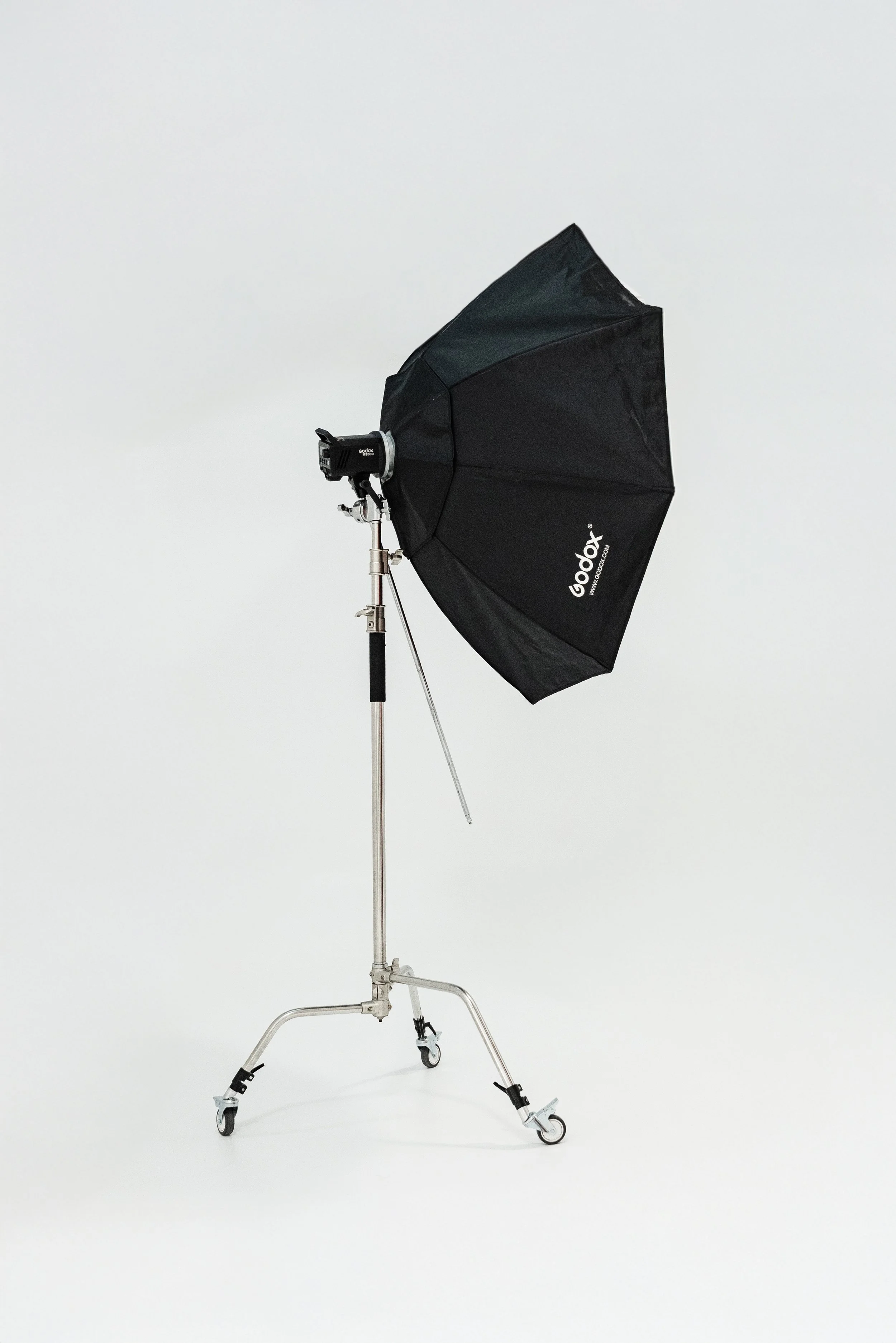 Photography lighting equipment, including a black Godox softbox on a stand with wheels, set against a plain white background.