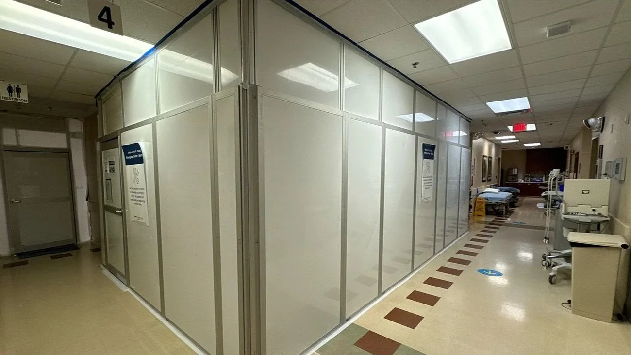 Hospital hallway with a privacy screen and medical equipment.