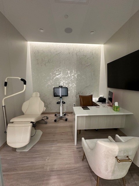 Dental office with examination chair, diagnostic equipment, desk with computer, and seating area.