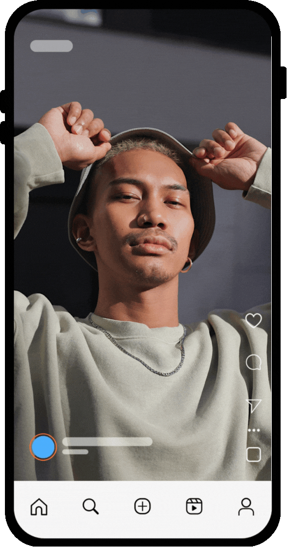 A young man with light brown hair and earrings, wearing a beige hoodie and chain necklace, adjusts a beige hat on his head while looking into the camera.