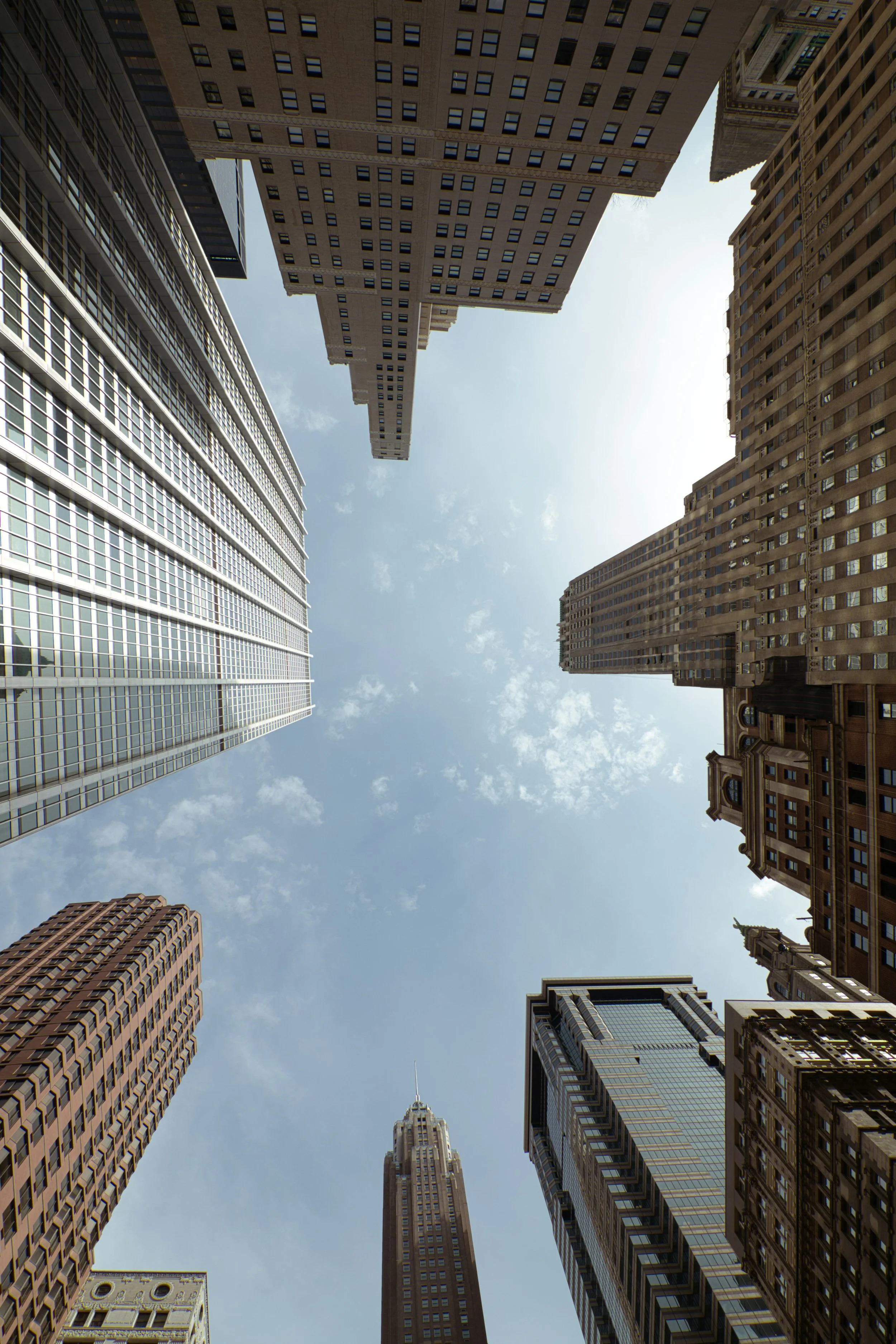 View of tall skyscrapers looking up at the sky in a city with a mix of modern and historic architecture.