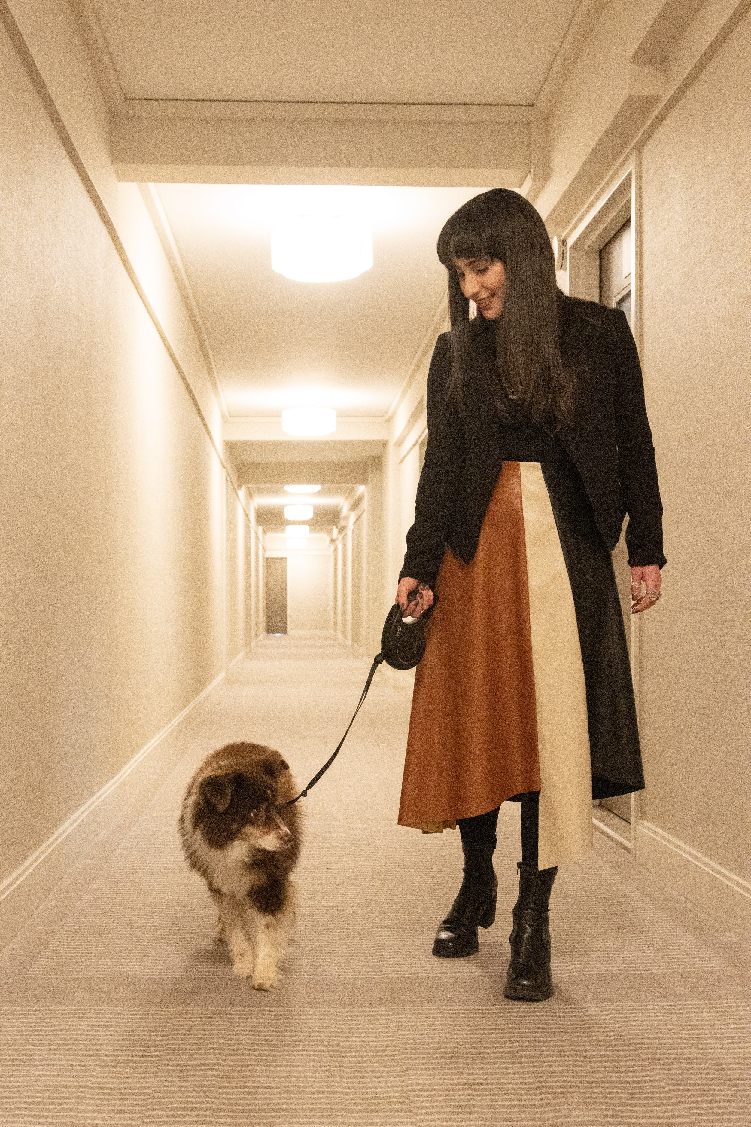 A woman walking her dog in a hotel hallway.