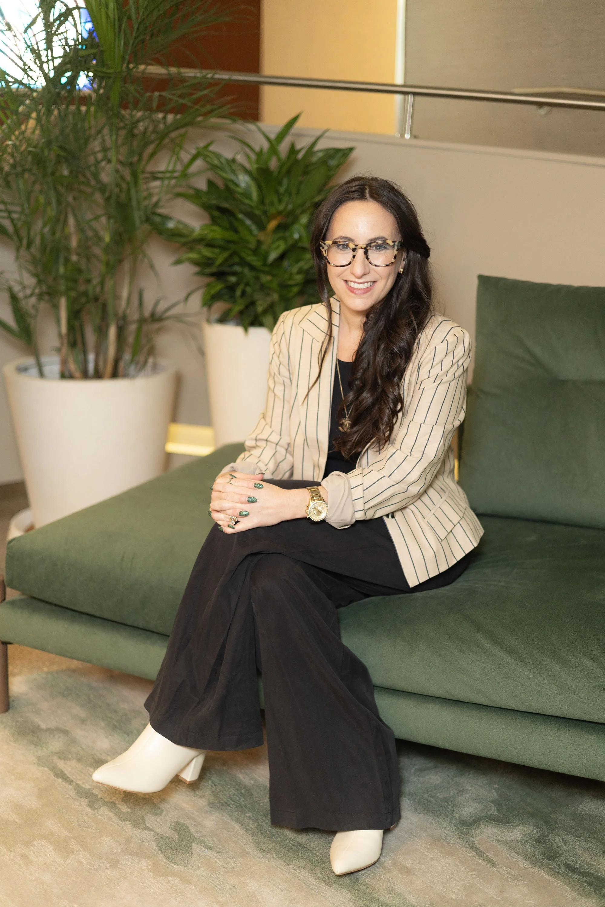 Madeleine in pinstripe jacket sitting on green couch