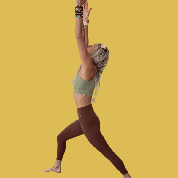 Person practicing yoga outdoors at sunset, in a pose with one leg extended and one arm reaching upward, by the water.
