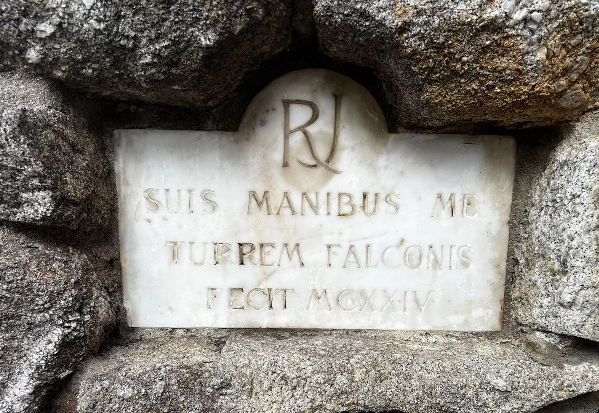 A marble plaque with Latin inscription, embedded in a stone wall. 'SUIS MANIBUS ME TURREM FALCONIS FECIT MCXXIX.'