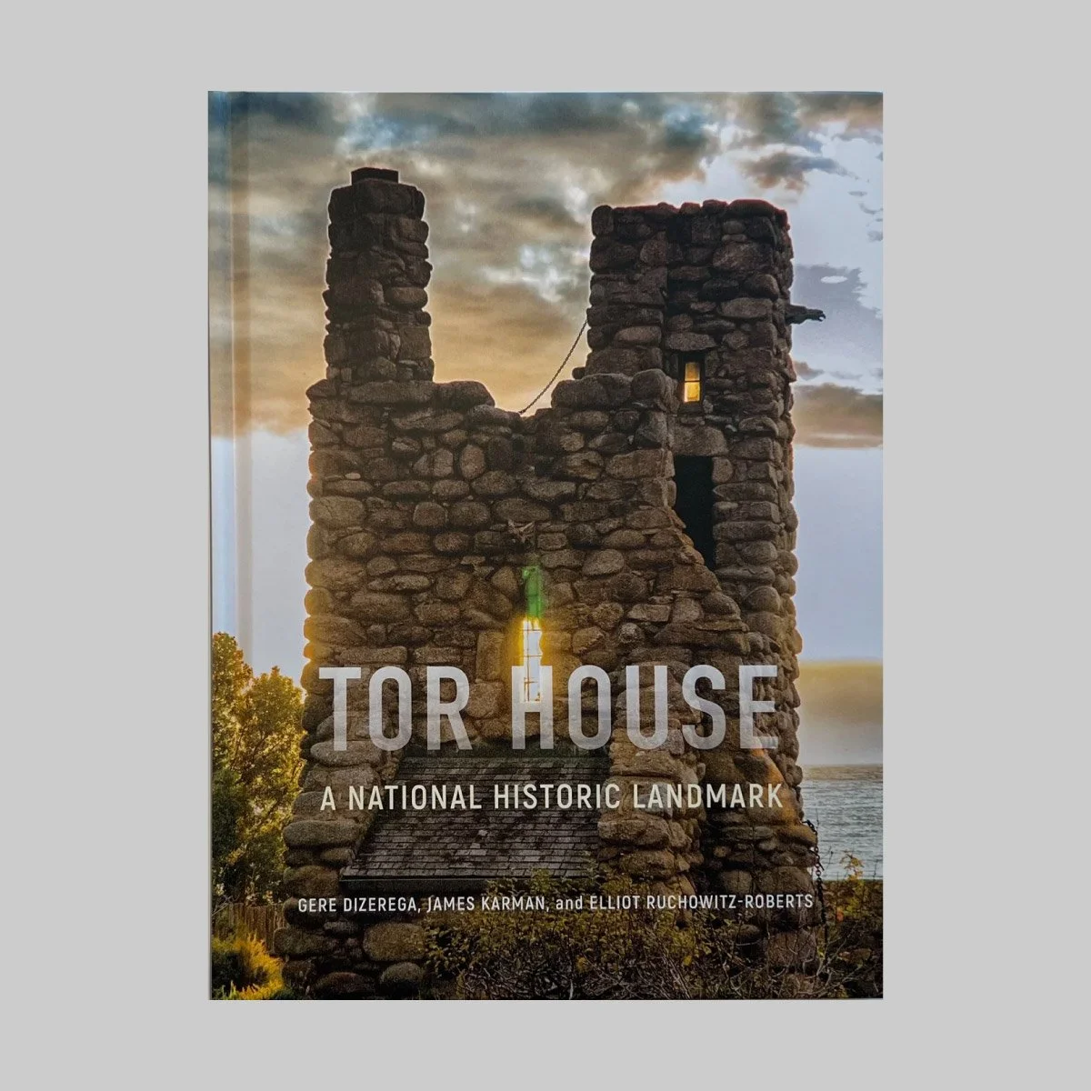 A book cover featuring a photo of a stone lighthouse with a glowing light at sunset, titled "Tor House: A National Historic Landmark" by Gere Dizerega, James Karman, and Elliot Ruchowitz-Roberts.
