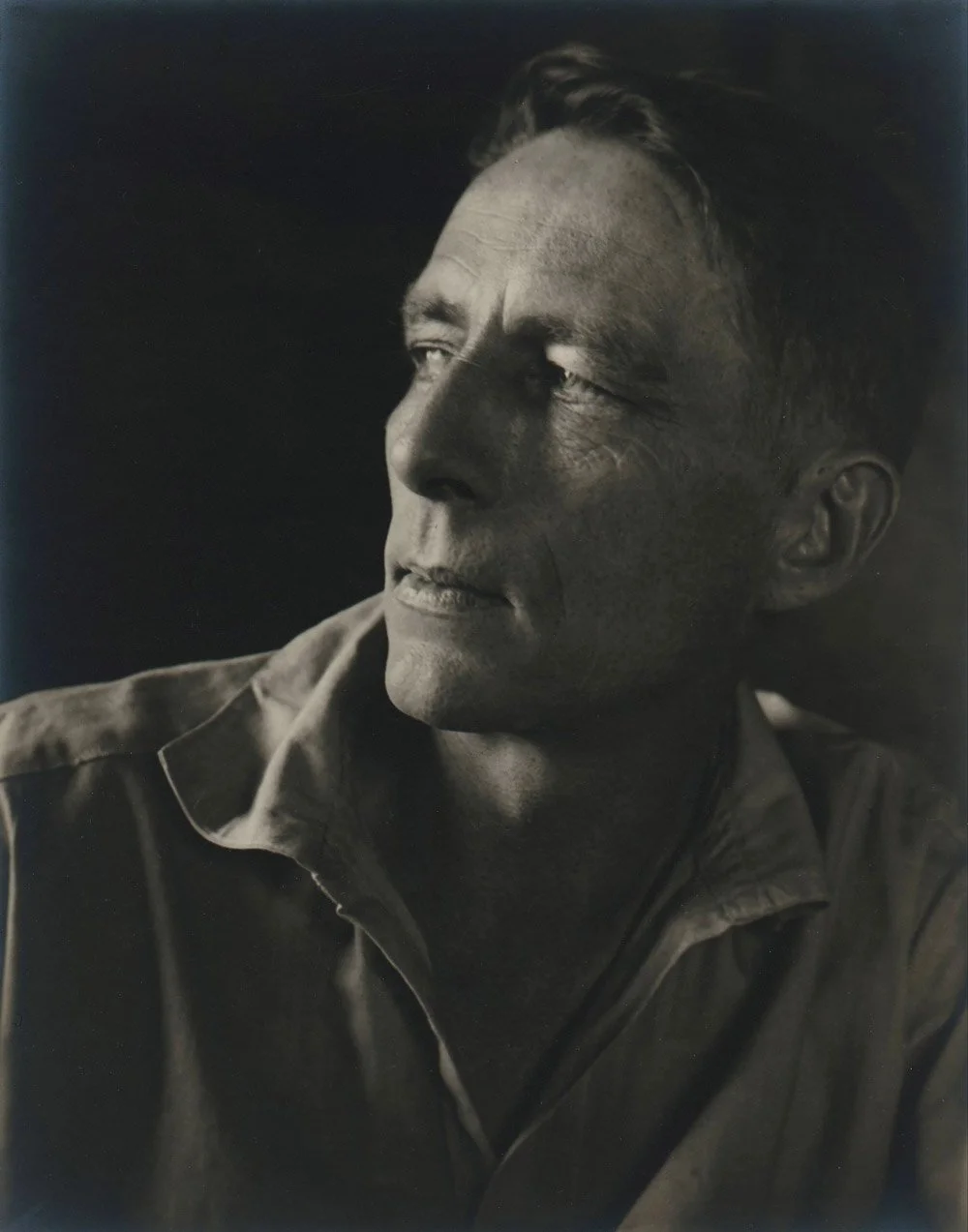 Black and white portrait photograph of a man with short hair, wearing a collared shirt, looking off to the side.