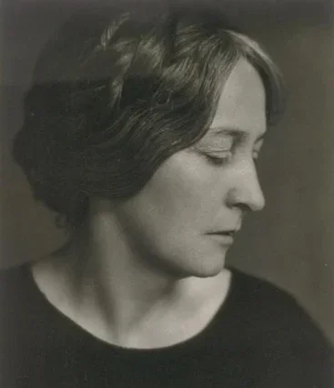 Black and white portrait of a woman in profile with short, wavy hair, wearing a dark top.