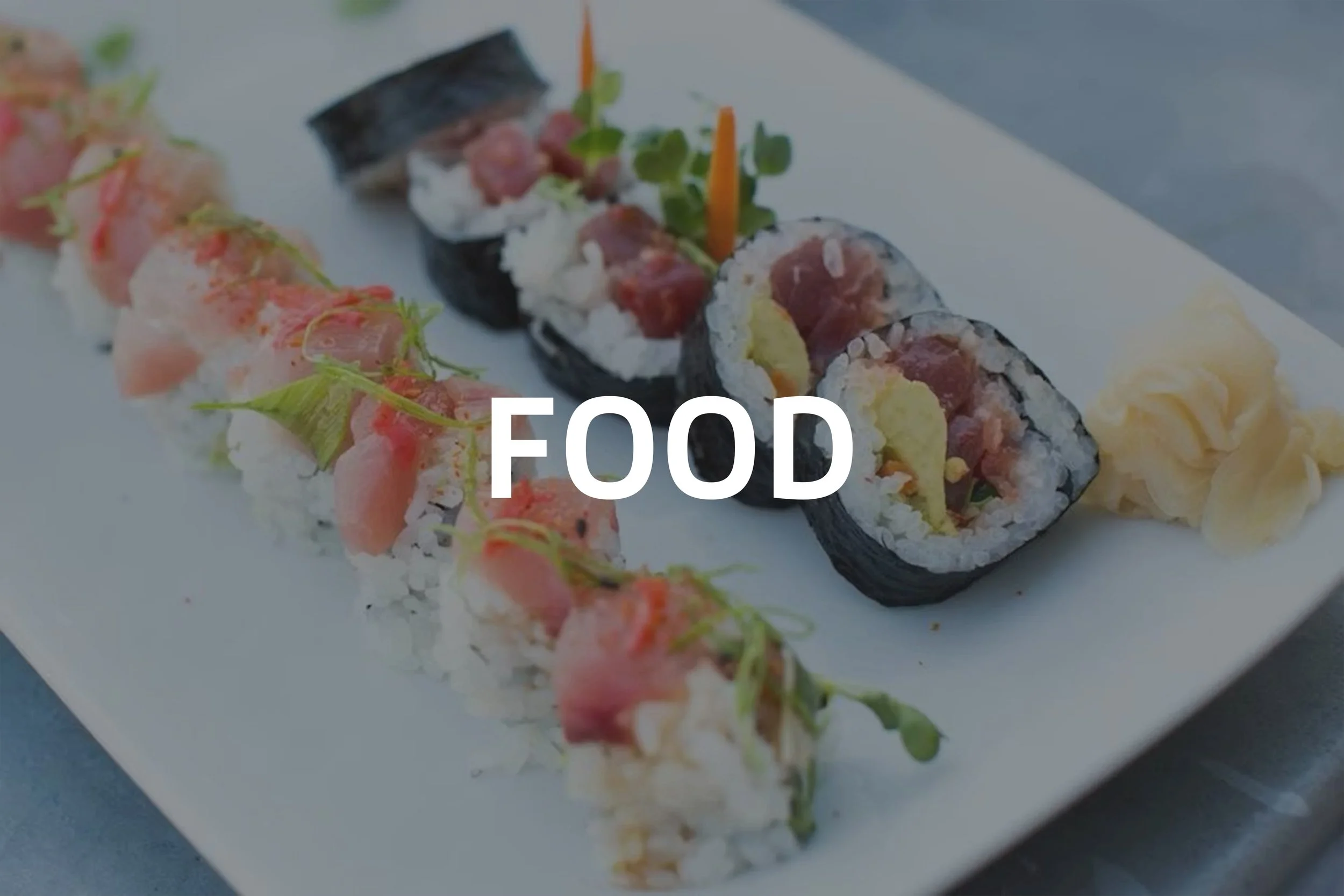 Plate of sushi rolls with slices of raw fish, rice, and vegetables, accompanied by pickled ginger.
