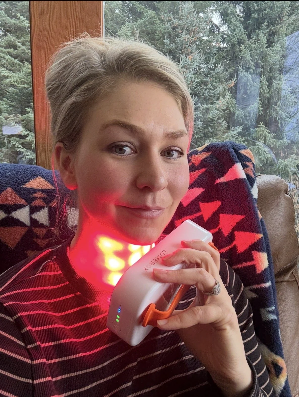 woman holding red light device to neck