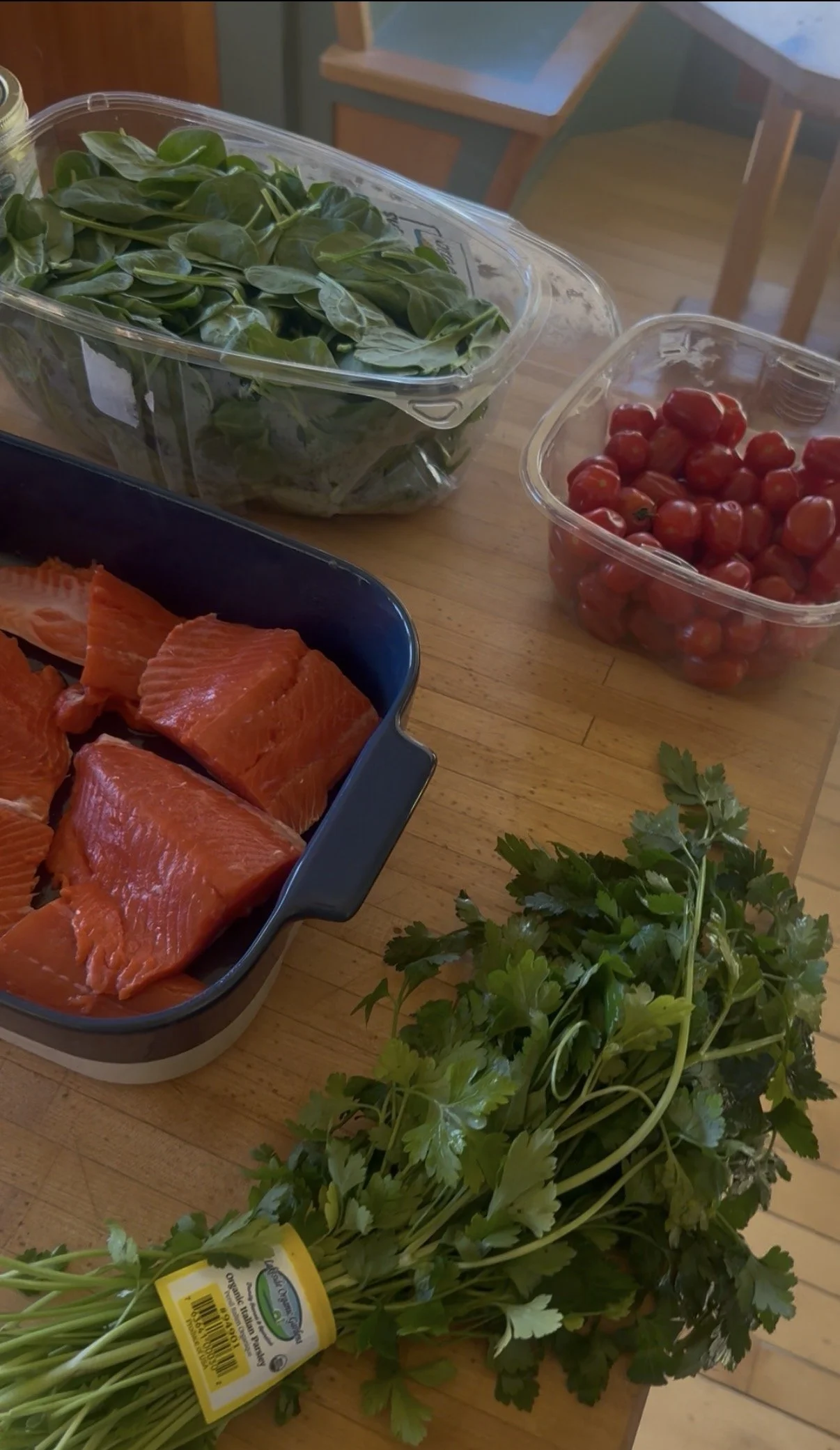 ingredients on a butcher block: Salmon, spinach, parsley, cherry tomatoes