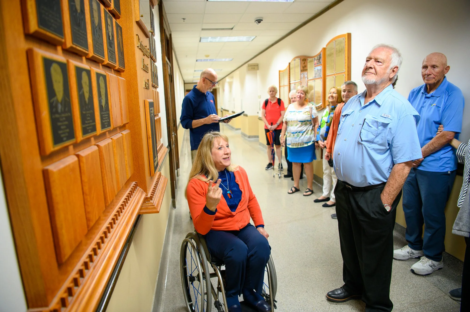 Jean Driscoll, director of advancement at the College of Applied Health Sciences and multi-time Paralympic champion wheelchair racer, shows off the wall of Distinguished Alumni Award winners to alums of the University of Illinois' vaunted sports psyc