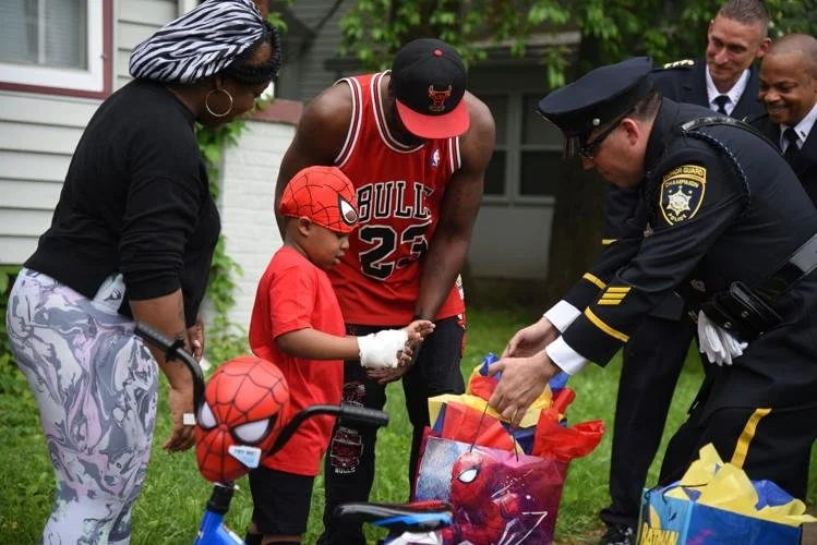 Kamryn Riley accepts superhero-themed gifts from members of the Champaign Police Department’s honor guard on May 21, 2022—his sixth birthday—outside his home near Church and Fourth streets. Kamryn was hurt in a shooting two days earlier near his home